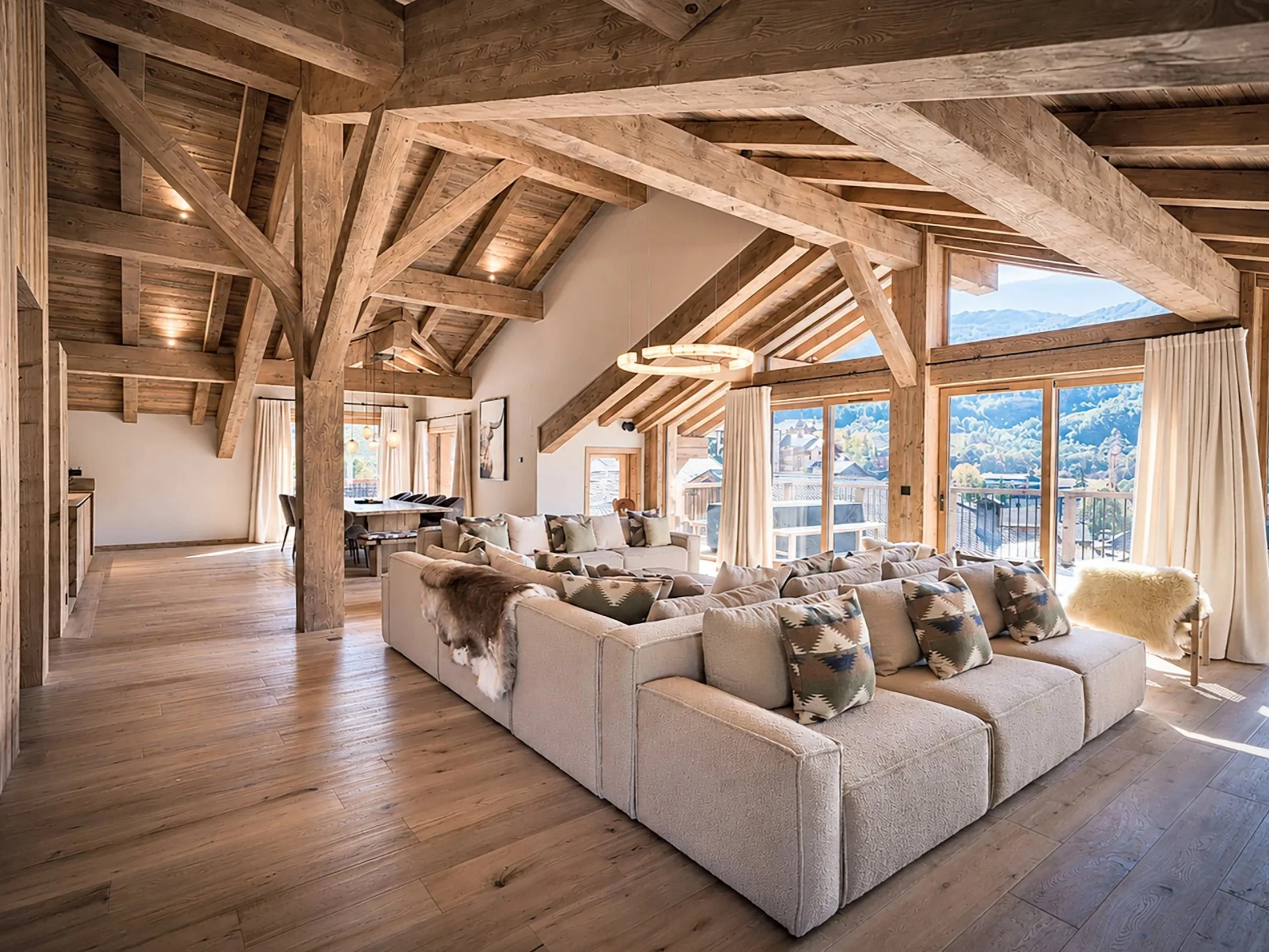 Salon spacieux d’un chalet de prestige à Saint-Martin-de-Belleville, charpente apparente, décoration alpine raffinée et terrasse avec vue montagne.