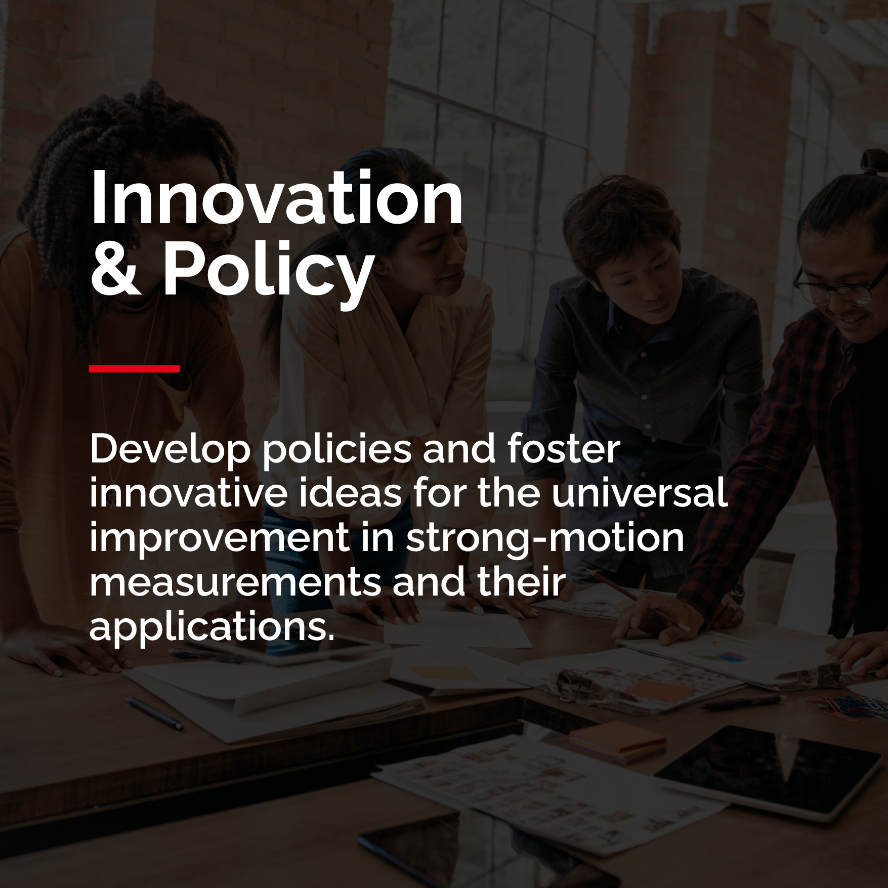 Group of people leaned over a table discussing innovation and policy for earthquake research.