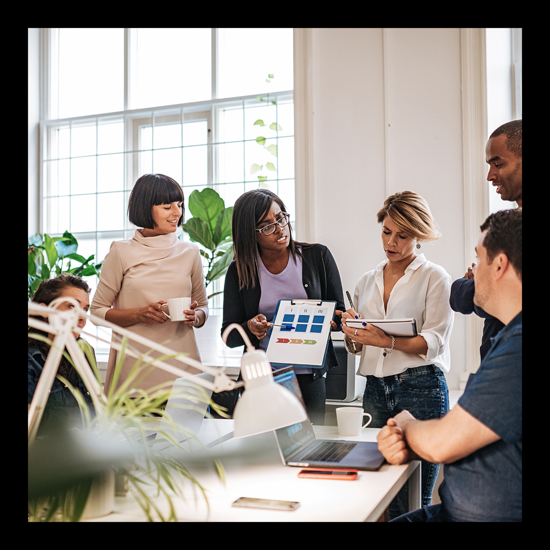 Group of professionals collaborating in a modern office, reviewing charts and data on a tablet during a team meeting.