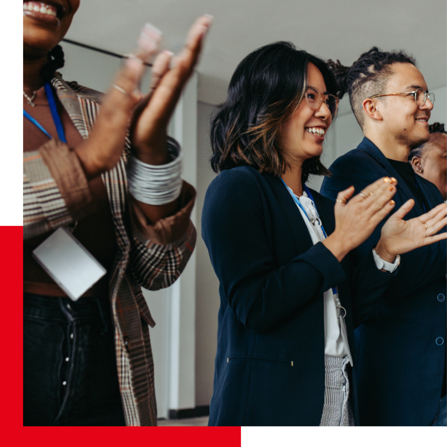 Group of professionals standing and applauding during an event, with a red corner design accent behind the photo.