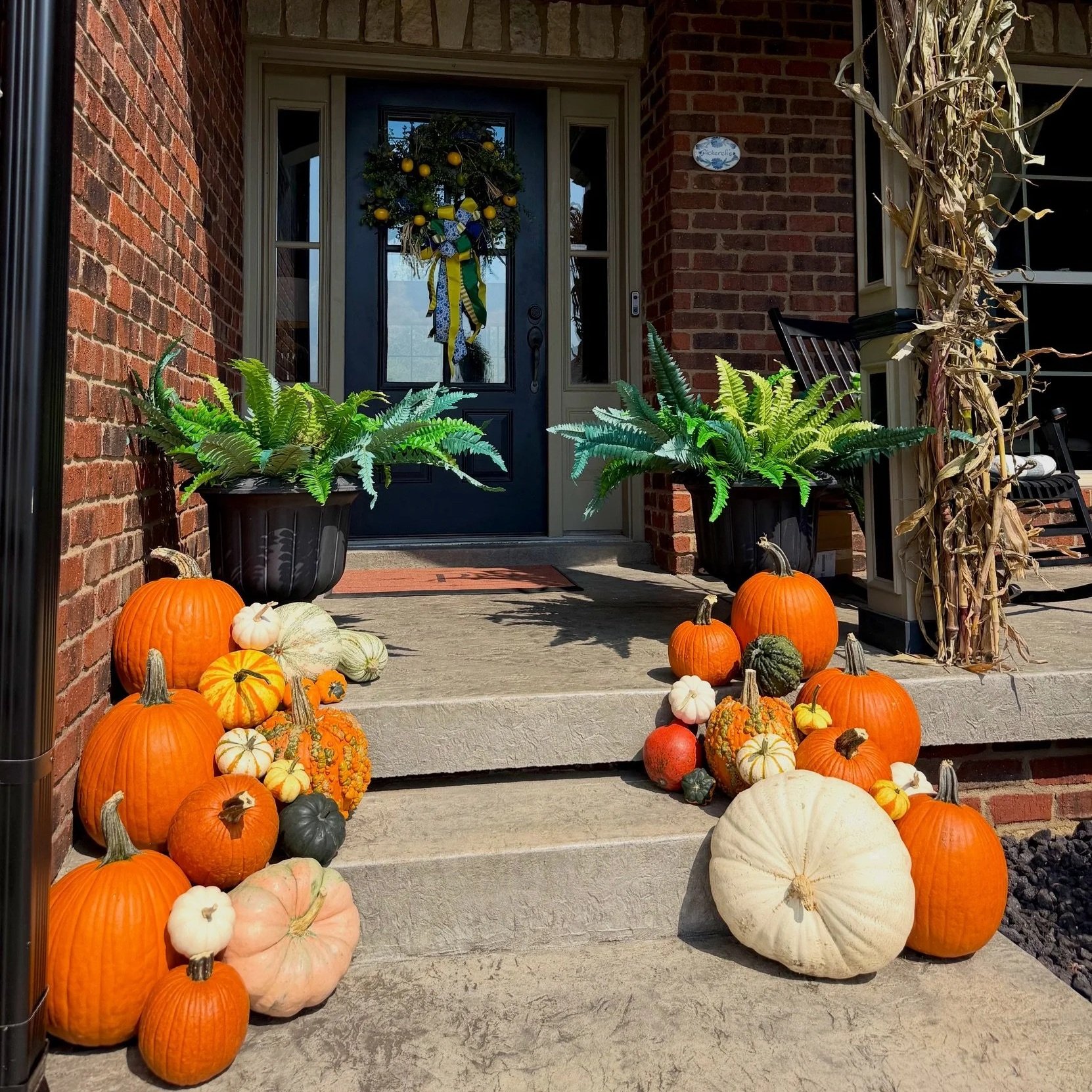 Custom fall porch decorating in Jeffersonville, IN with stacked pumpkins, cornstalks, and luxury autumn styling.