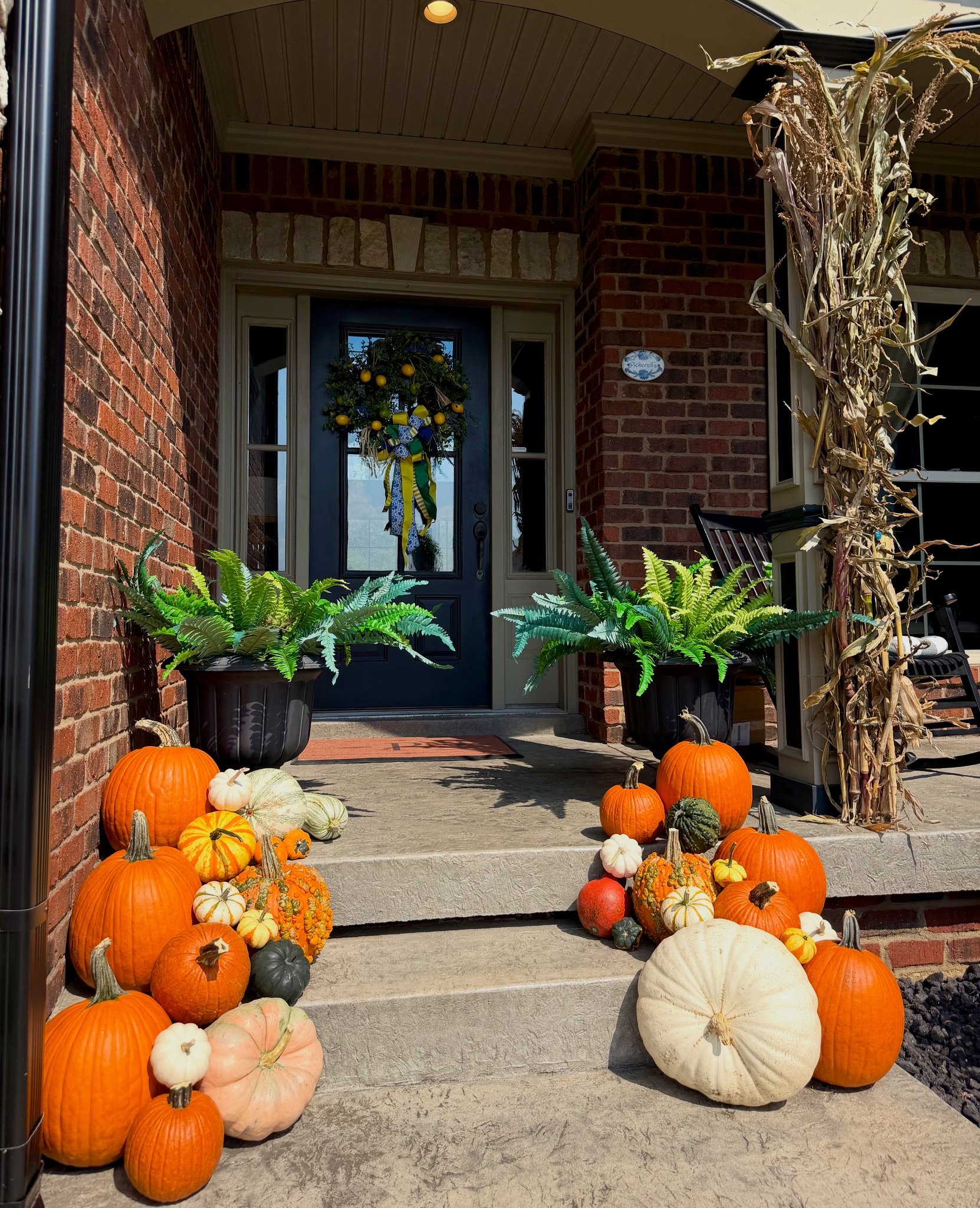 Custom fall porch decorating in Jeffersonville, IN with stacked pumpkins, cornstalks, and luxury autumn styling.
