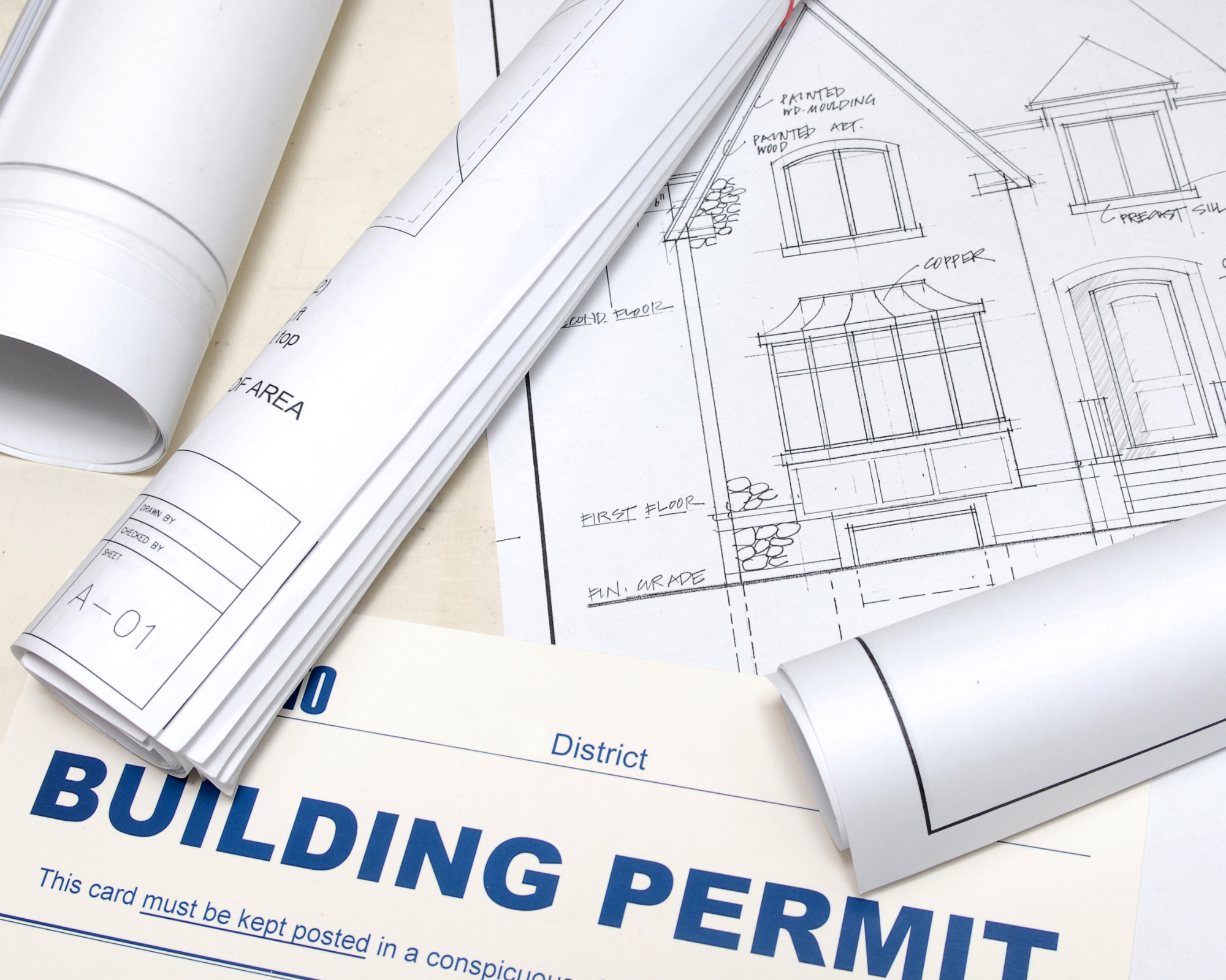 Architectural blueprints and a building permit card on a desk.