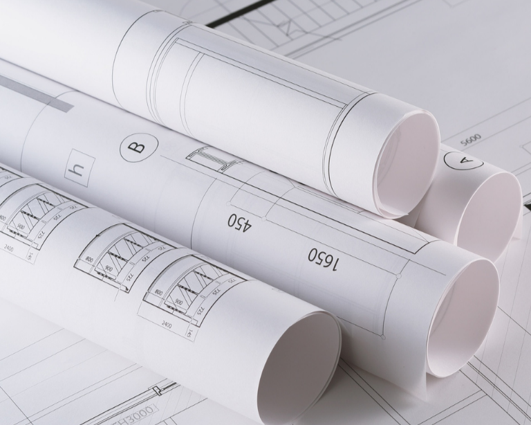 Architectural blueprints and rolled-up drawings on a flat surface.
