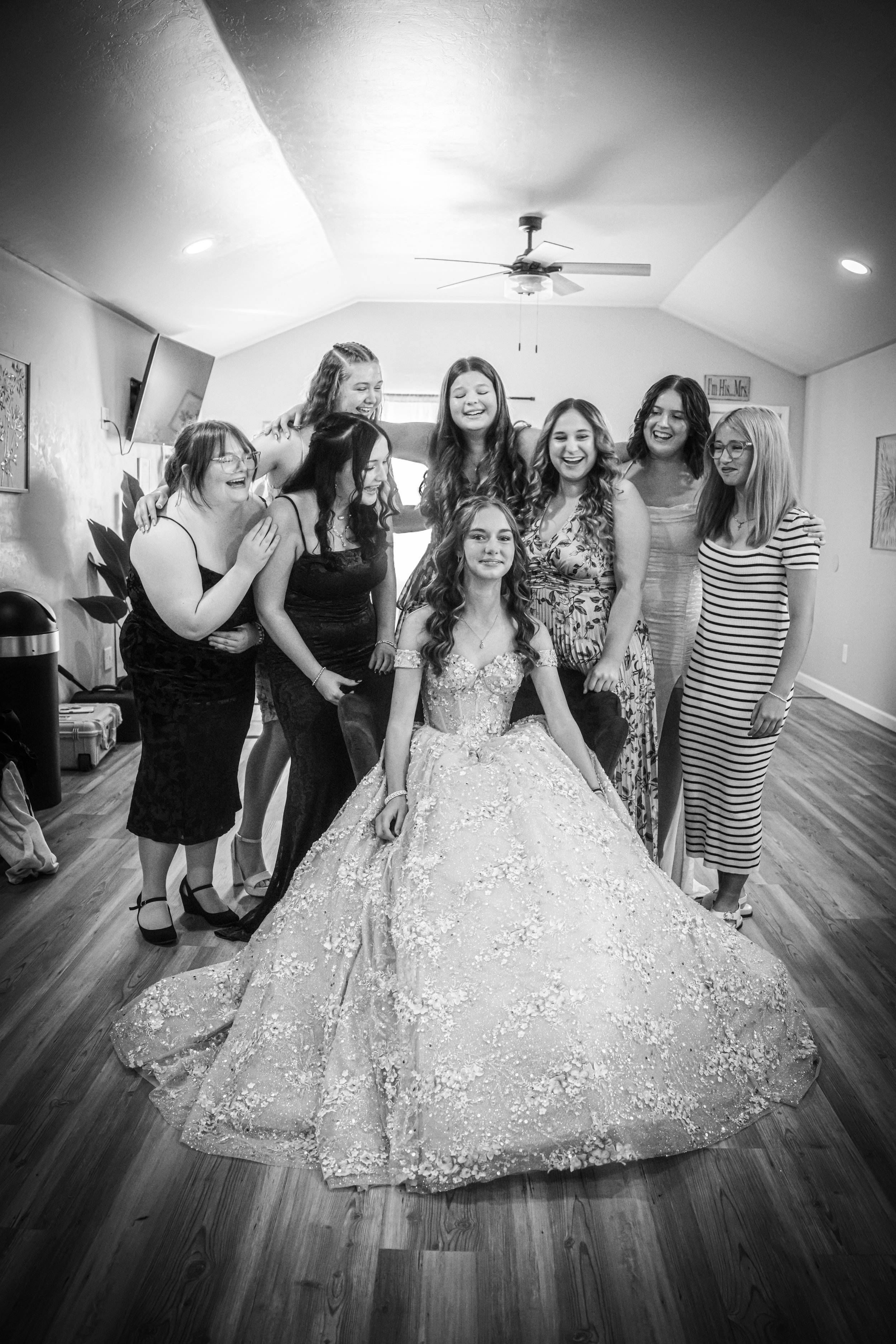 Group of young women, one wearing a wedding dress, celebrating in a room.