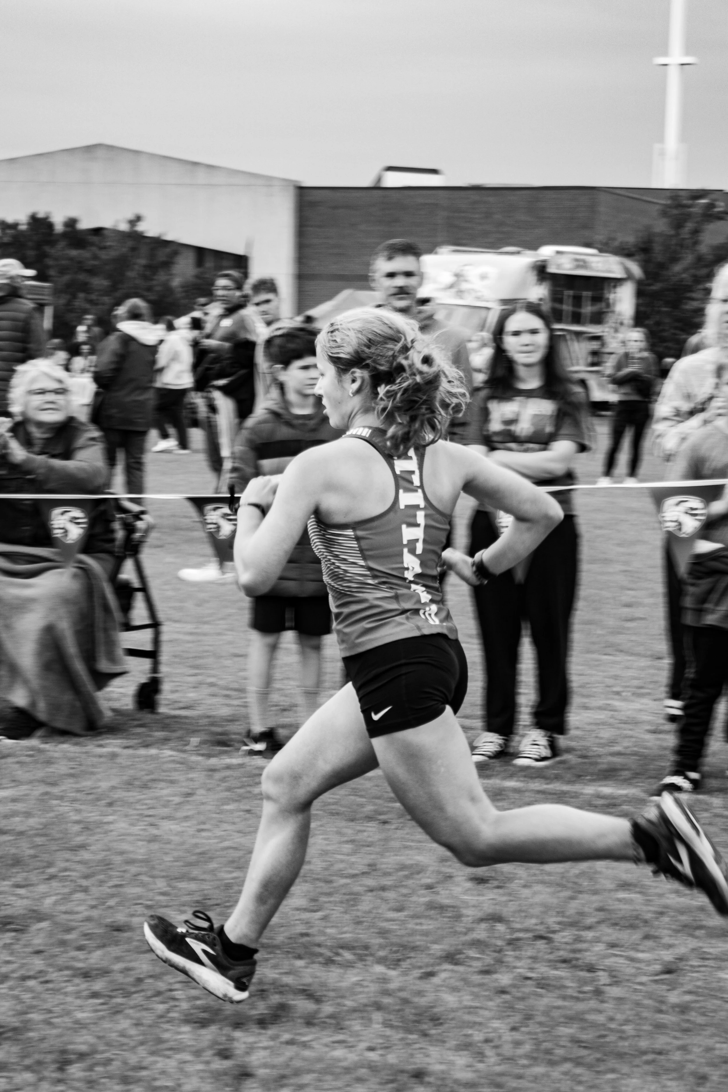 A female runner in a race, mid-stride, surrounded by spectators at the finish line.