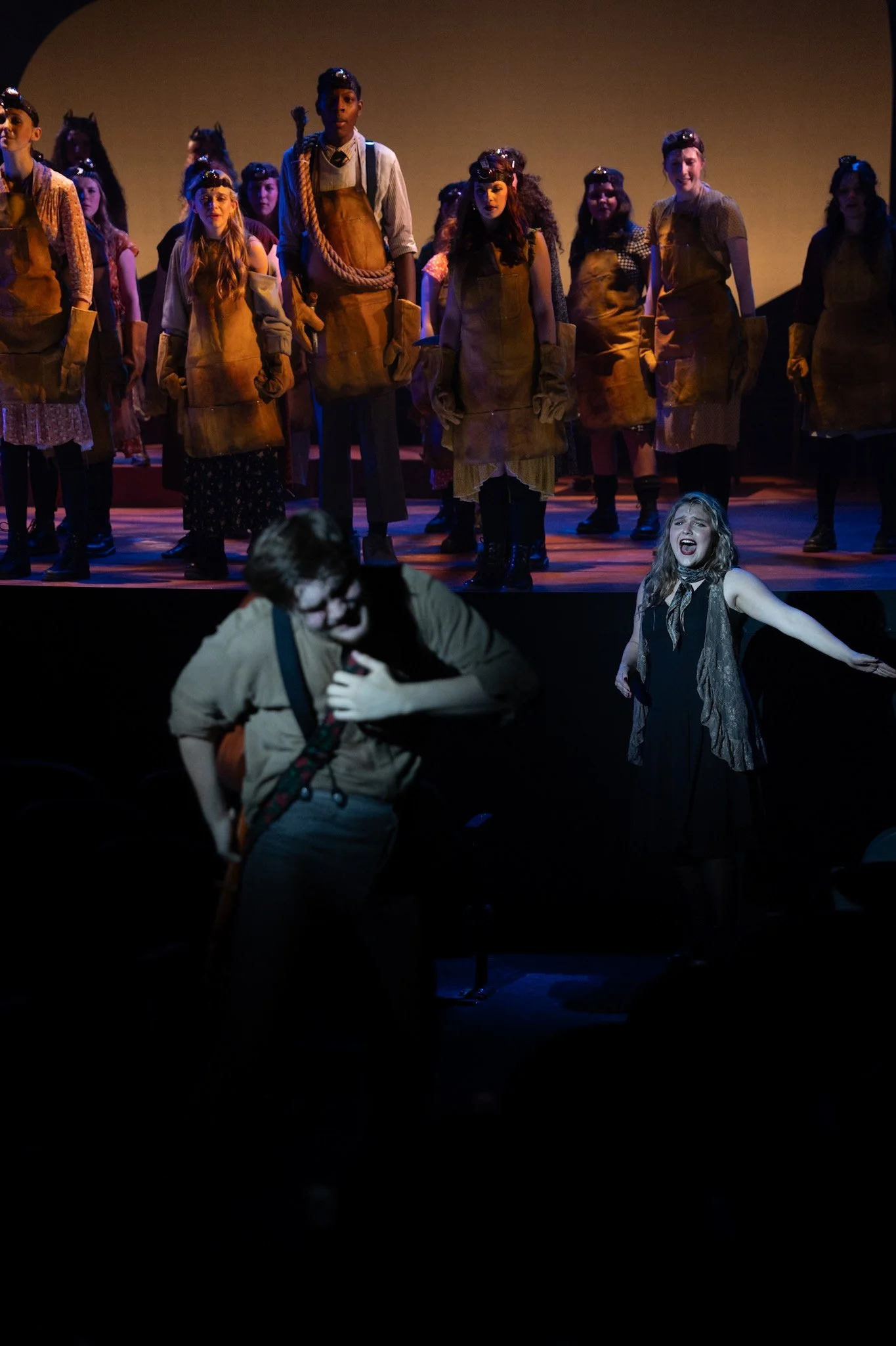 Stage performance with a group of actors, some in costume, on stage during a play or musical.