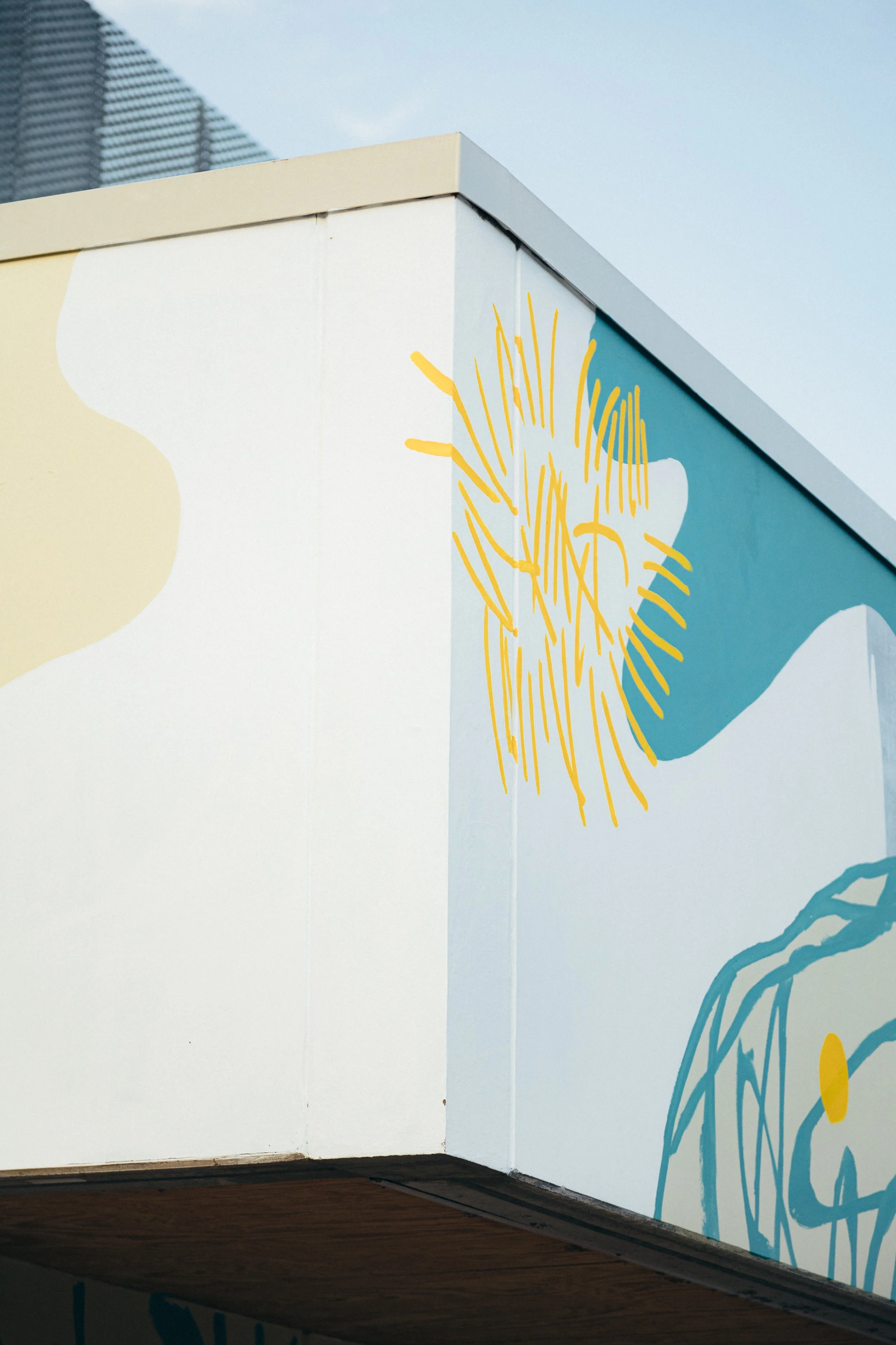 Muro con decorazioni colorate, elementi di design astratti e linee stilizzate di fiori e natura, con sfondi in tonalità di blu e giallo.