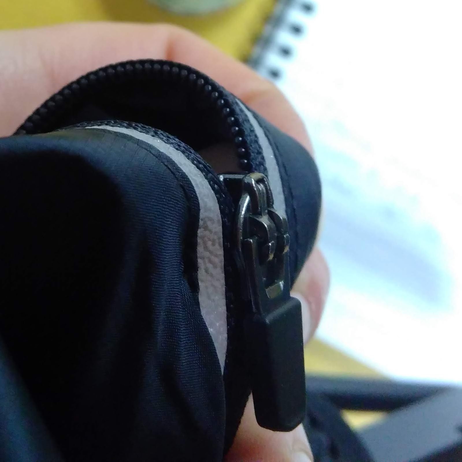 Close-up of a person's hand holding a black camera with a strap, taken from a first-person perspective.