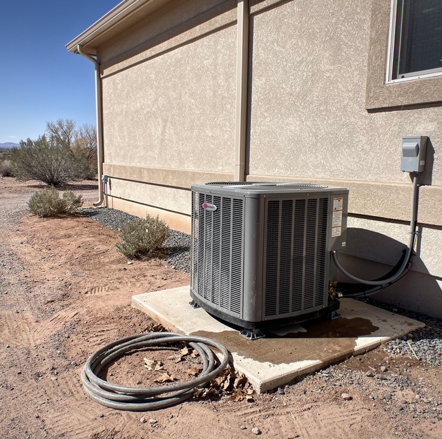 central air conditioning condenser unit beside house