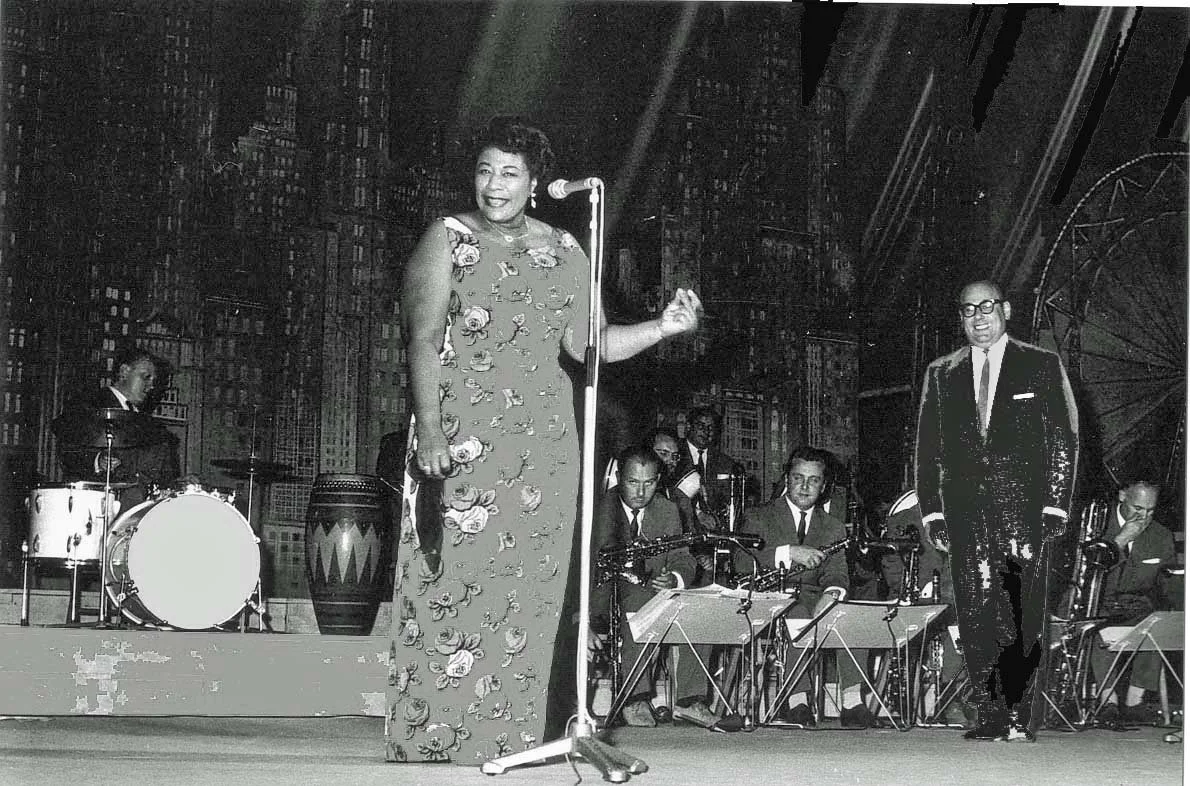 Ella Fitzgerald und Johannes Fehring gemeinsam im Konzert mit Orchester im Hintergrund.