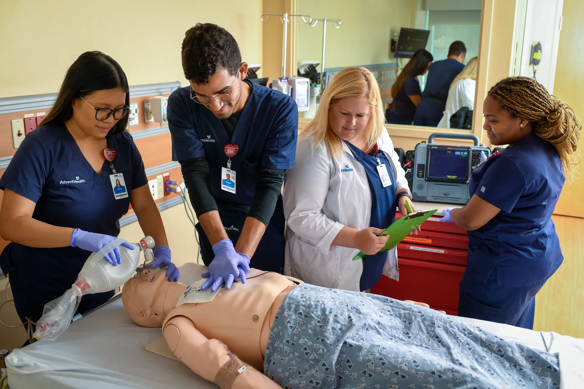A group of healthcare professionals performing CPR on a mannequin in a hospital room.