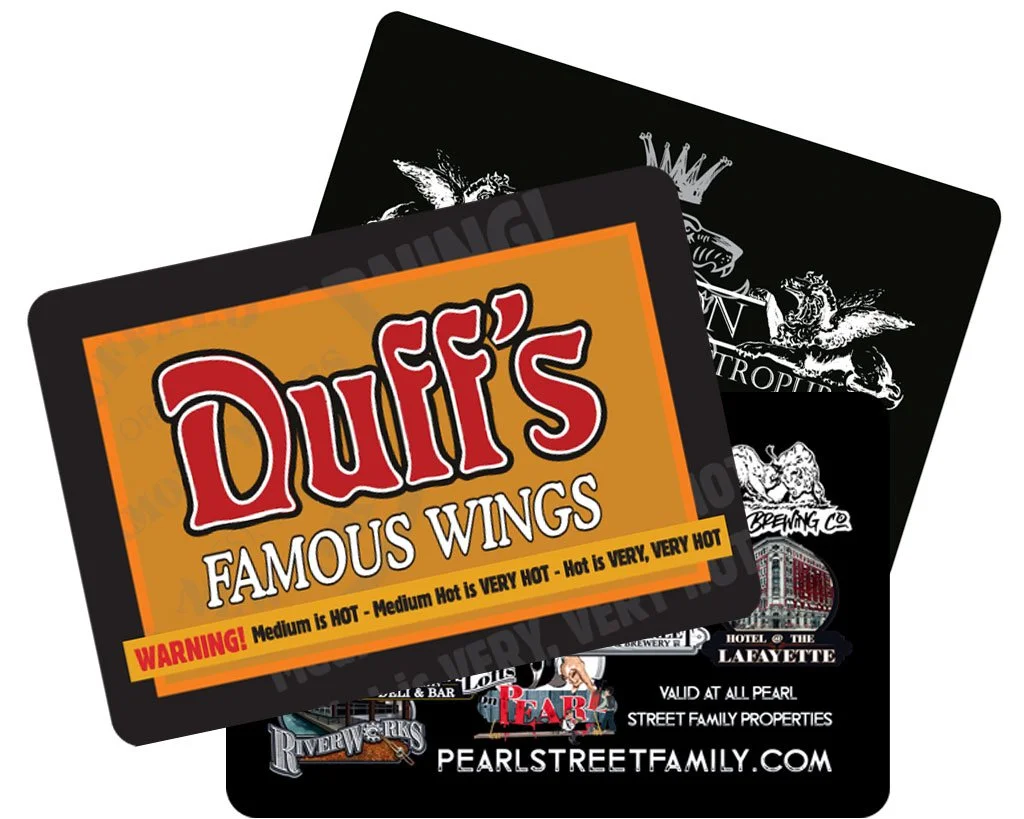 Two overlapping business cards or flyers for Pearl Street Family, featuring a honey mustard-colored card for Duffy's Famous Wings with bold red and white text and a warning label about spice levels, and a black card with white detailed logos of various establishments.