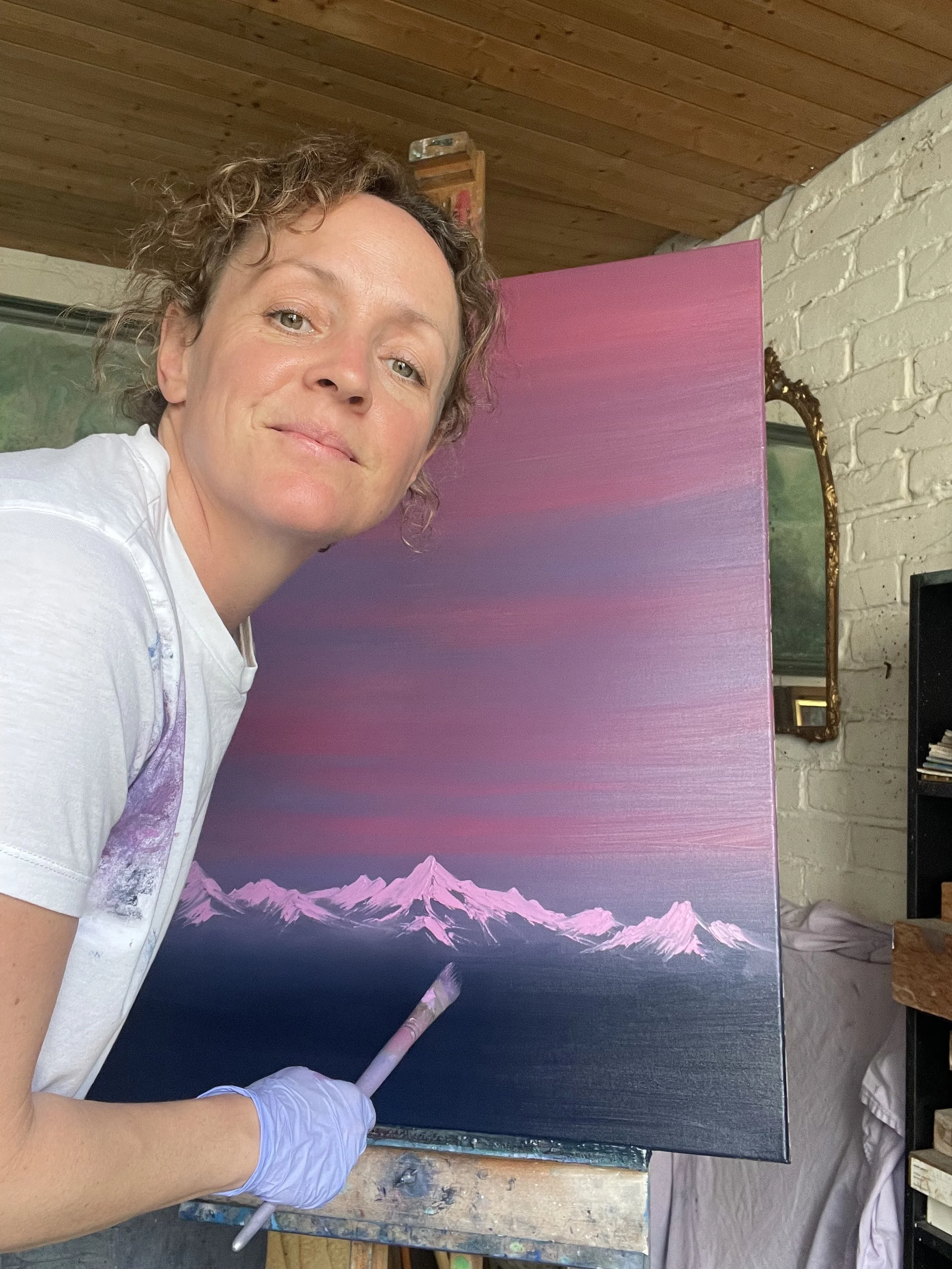 Contemporary artist Cat Goward painting mountain landscapes in her studio