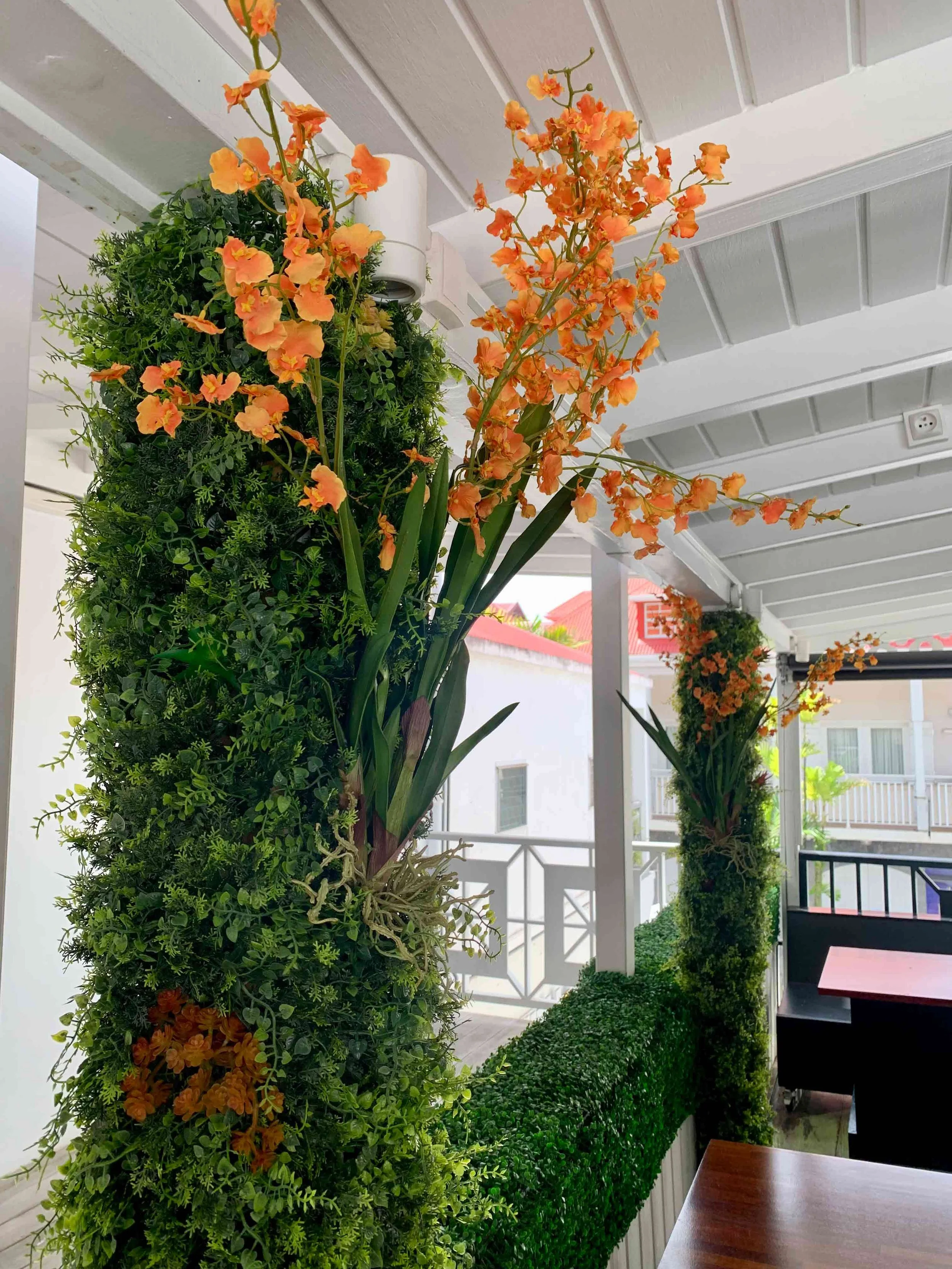 Tall artificial tree with orange flowers adding vibrant tropical color to an indoor space in St Barth.
