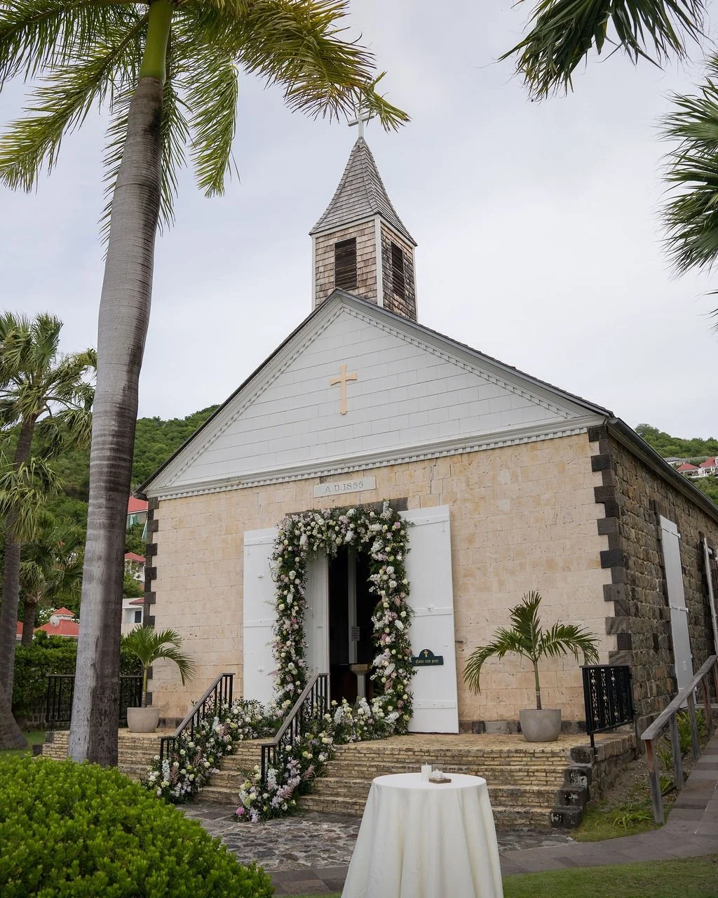 A doorway transformed into a floral welcome.
ㅤ
For this wedding at the Anglican Church of St Barth, we designed a soft and romantic floral frame around the entrance, blending white blooms, delicate blush touches and generous greenery.
ㅤ
The idea was 