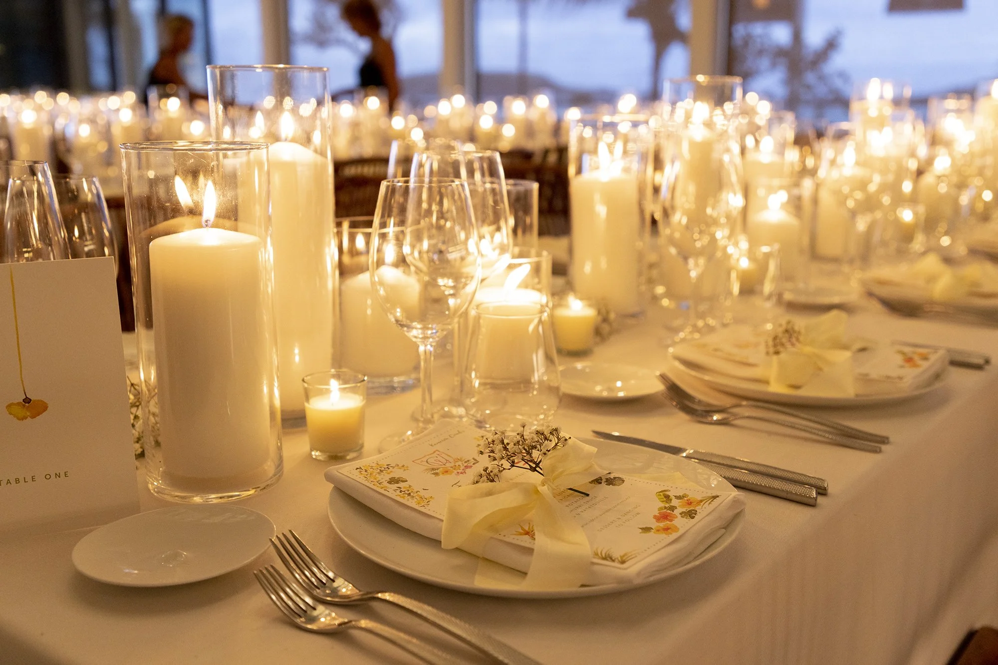 Table élégamment dressée avec des bougies dans des photophores et des verres à vin, décorée pour un dîner de mariage ou une fête festive dans une ambiance chaleureuse