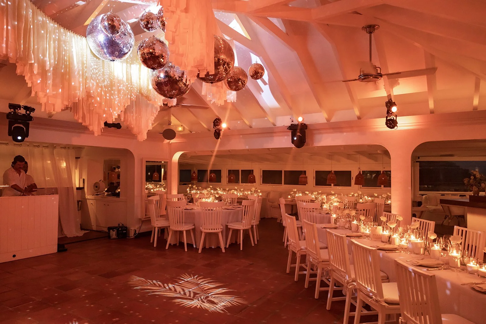 Elegant indoor wedding reception with hanging decor, white tables, and candlelit ambiance in St Barth.