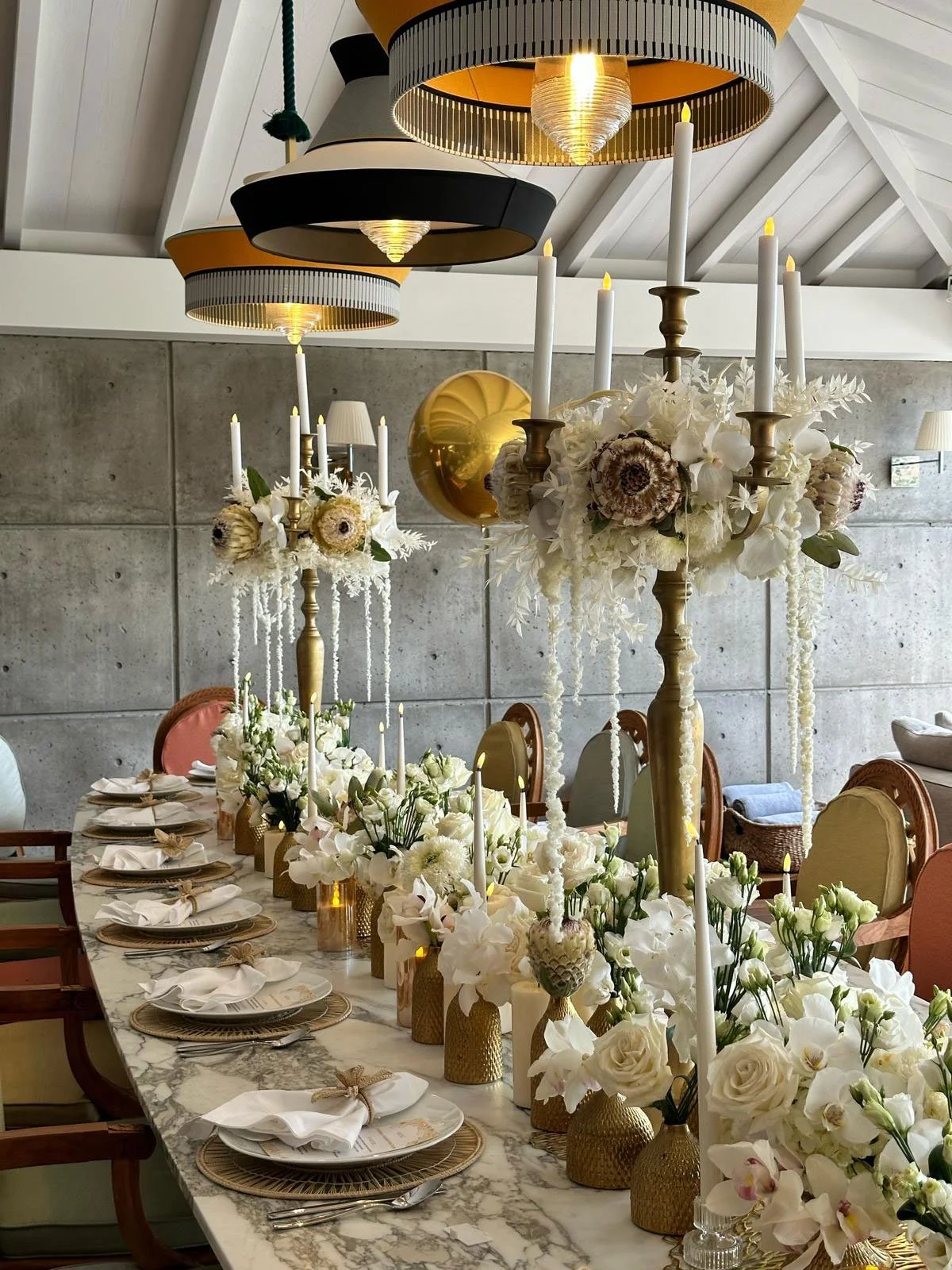 Modern wedding table setup with white flowers, gold candles, and refined design in St Barth.
