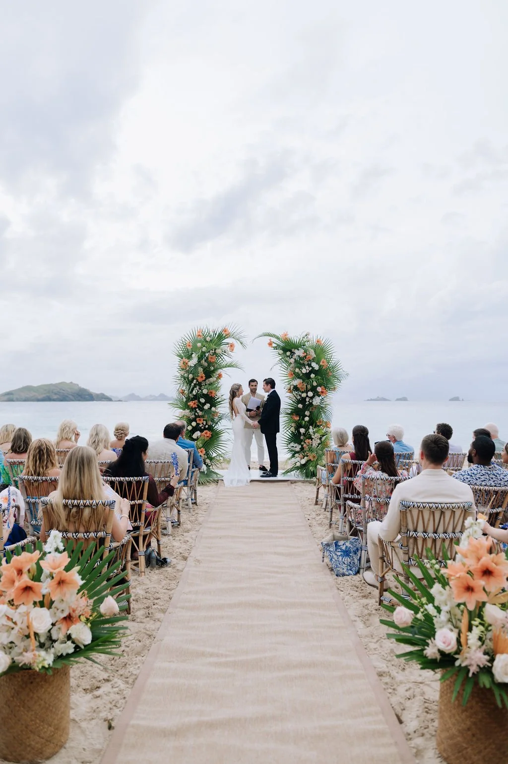 Beachside wedding ceremony with floral arch, guests, and ocean views in St Barth.