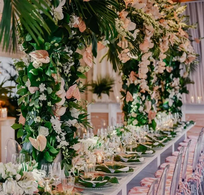 Festive table decorated with a large floral arch arrangement featuring green leaves and white and pink flowers for an elegant event in St Barth.