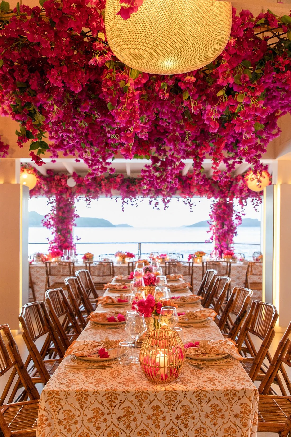 Luxury wedding dinner table with fuchsia floral arrangements, golden accents, and candlelight ambiance in St Barth.