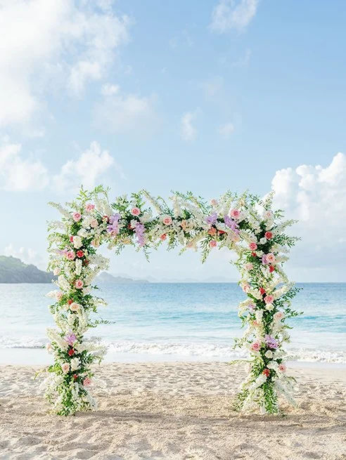 Elegant beach wedding arch decorated with white and green flowers, facing the ocean in St Barth.
