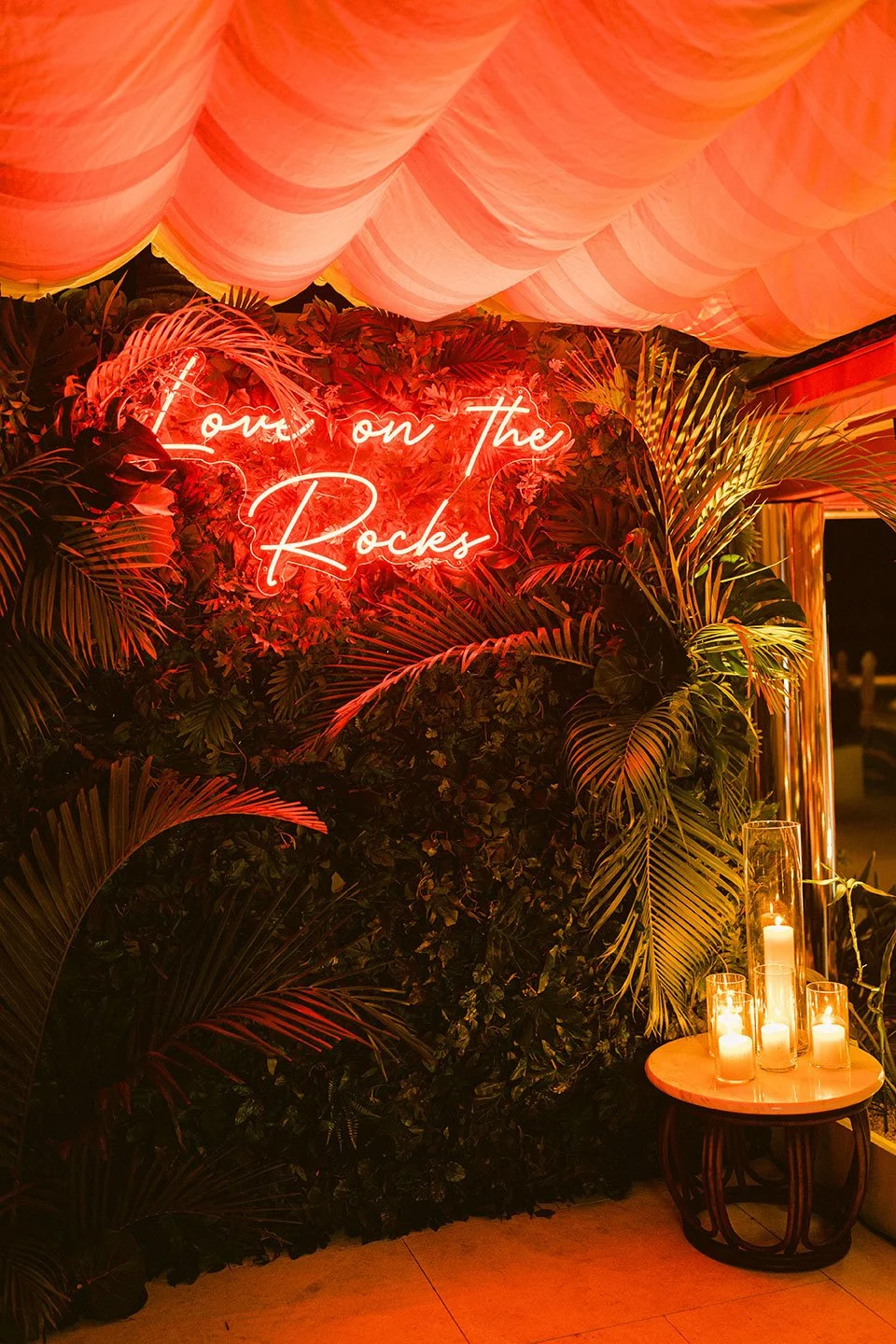 Tropical greenery wall with neon sign ‘Love on the Rock’ for a romantic wedding celebration in St Barth.