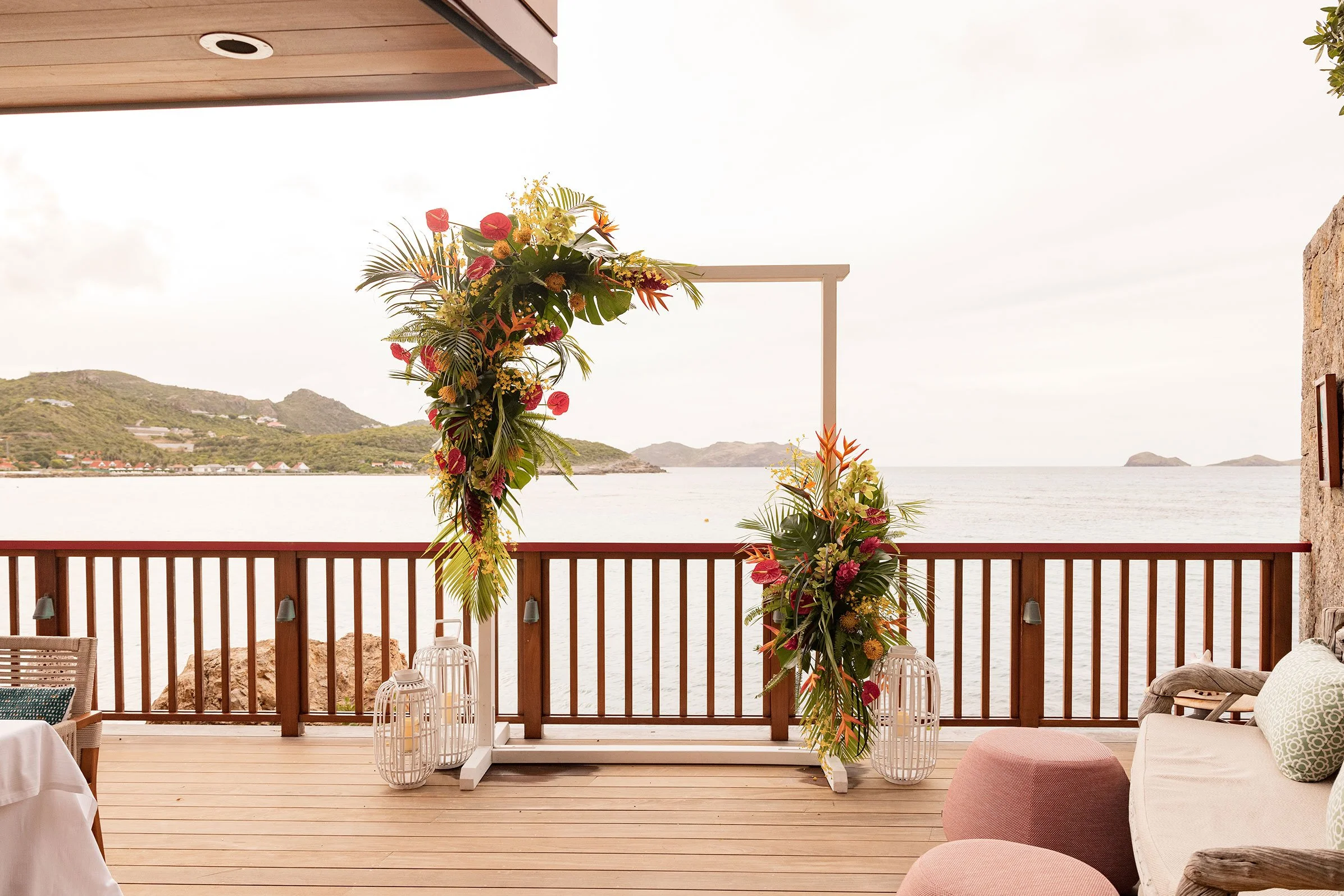 Vibrant wedding floral arch with red and orange tropical flowers overlooking the Caribbean Sea in St Barth.