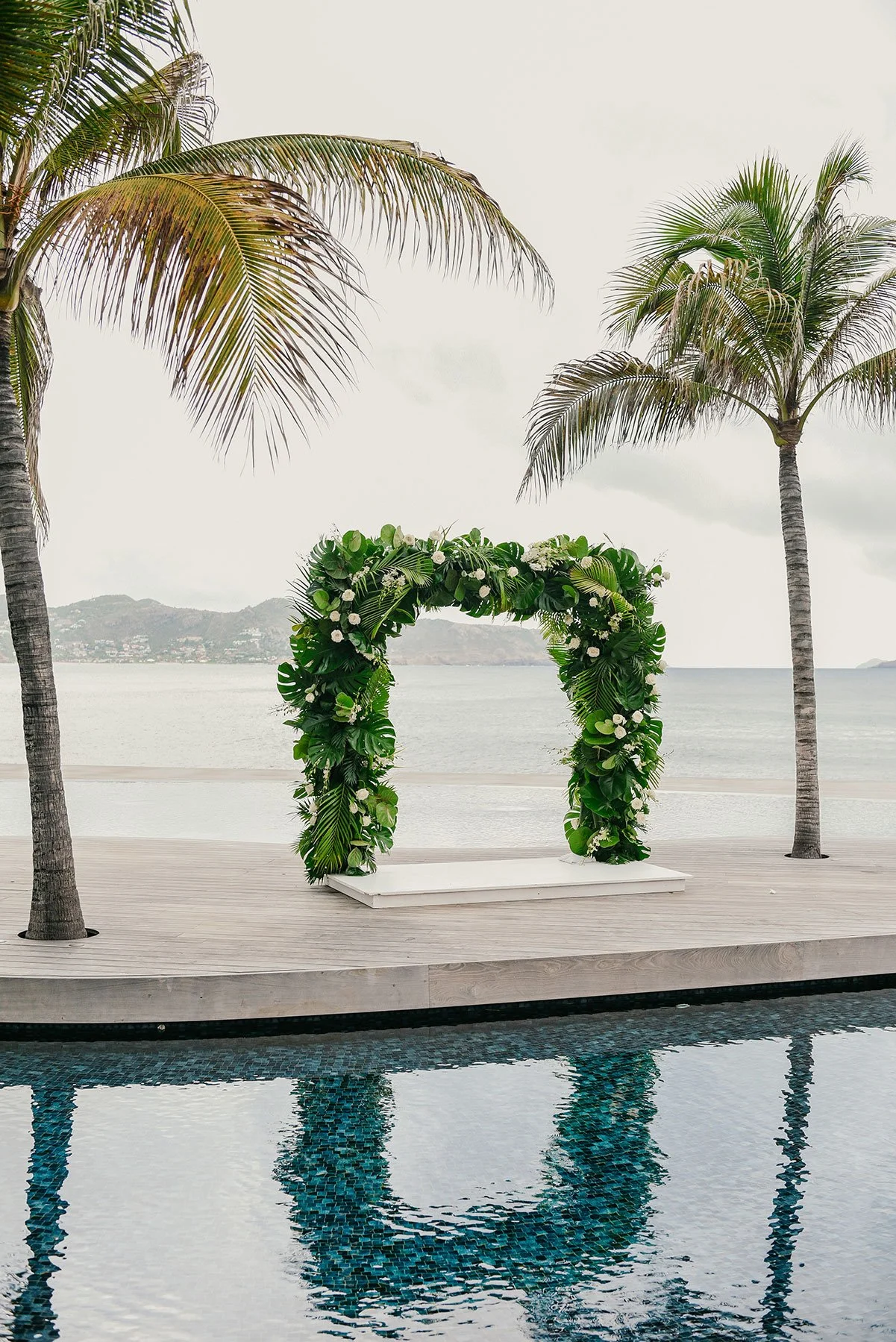 Minimalist tropical floral arch with lush greenery and ocean views for an intimate wedding in St Barth.