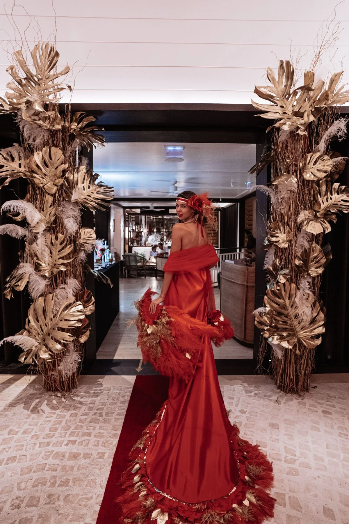 Glamorous wedding entrance decorated with gold and dried flowers, featuring a bride in a red gown in St Barth.