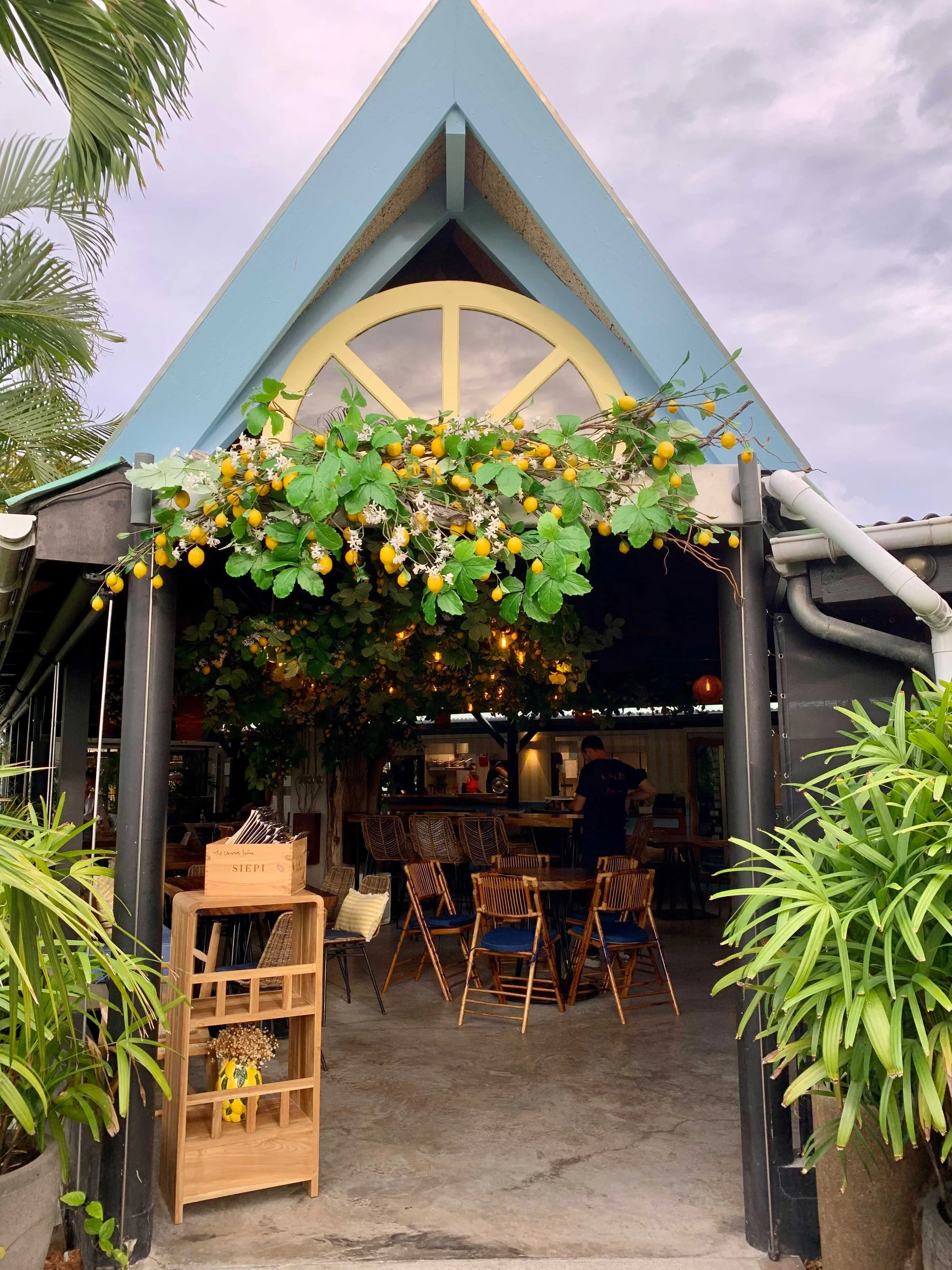 Restaurant entrance decorated with green foliage, white flowers, and yellow lemons for a tropical and elegant setting in St Barth.