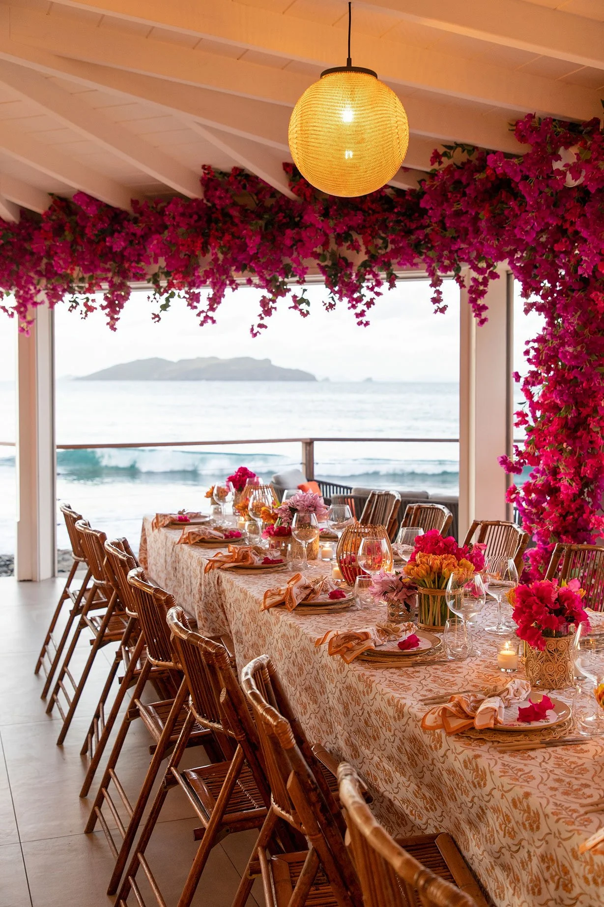Romantic seaside dinner table with pink floral arrangements and golden sunset views in St Barth.