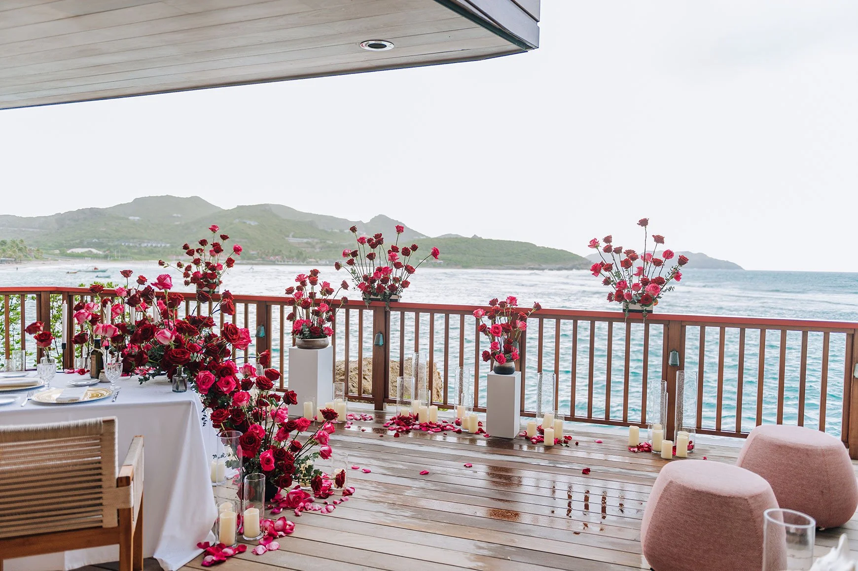 Stunning floral arch with red and pink roses decorating a seaside terrace for a luxury wedding in St Barth.