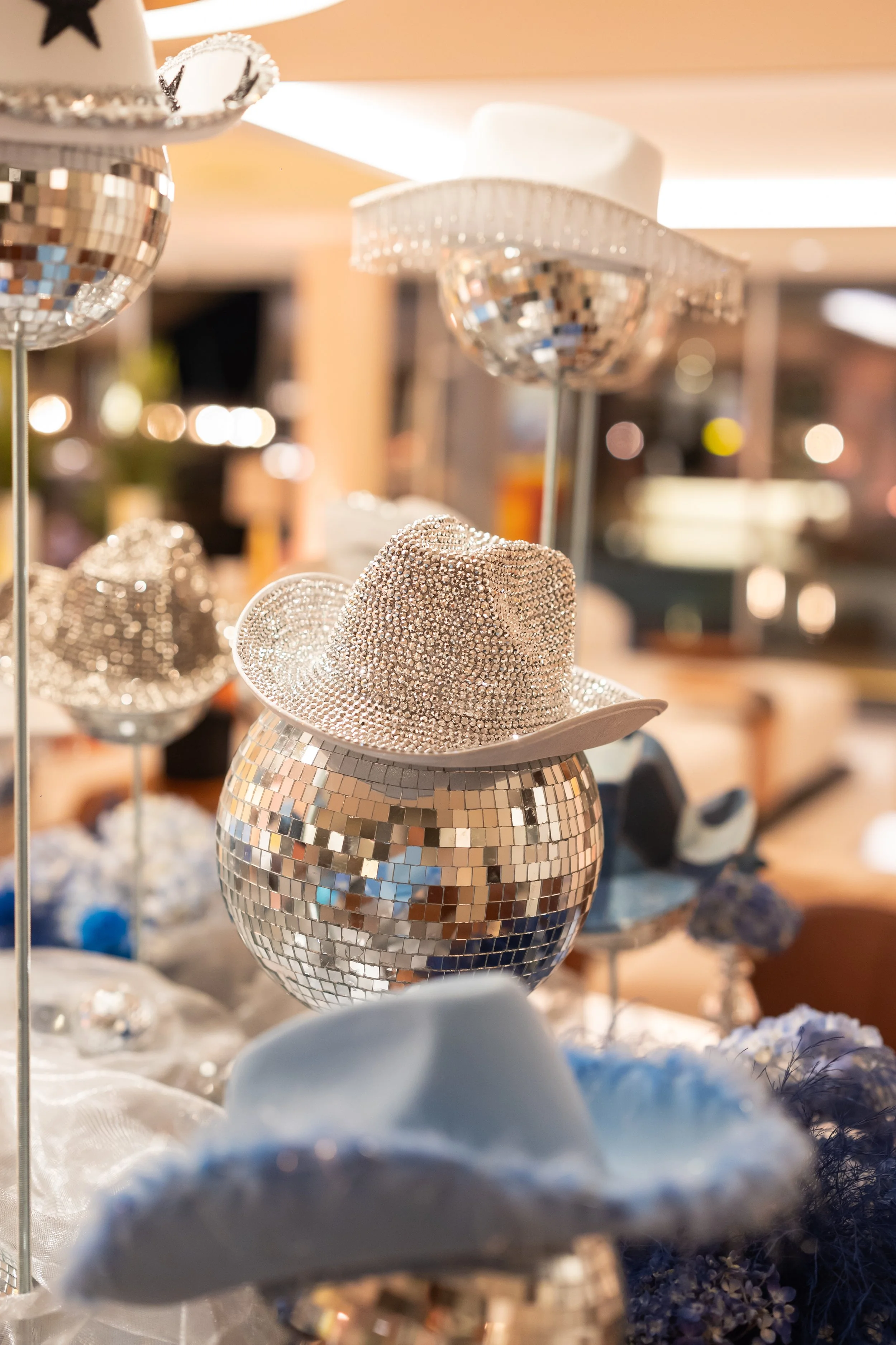 Capteurs décoratifs en forme de chapeaux, couverts de miroirs, exposés sur des supports dans un magasin ou une exposition.