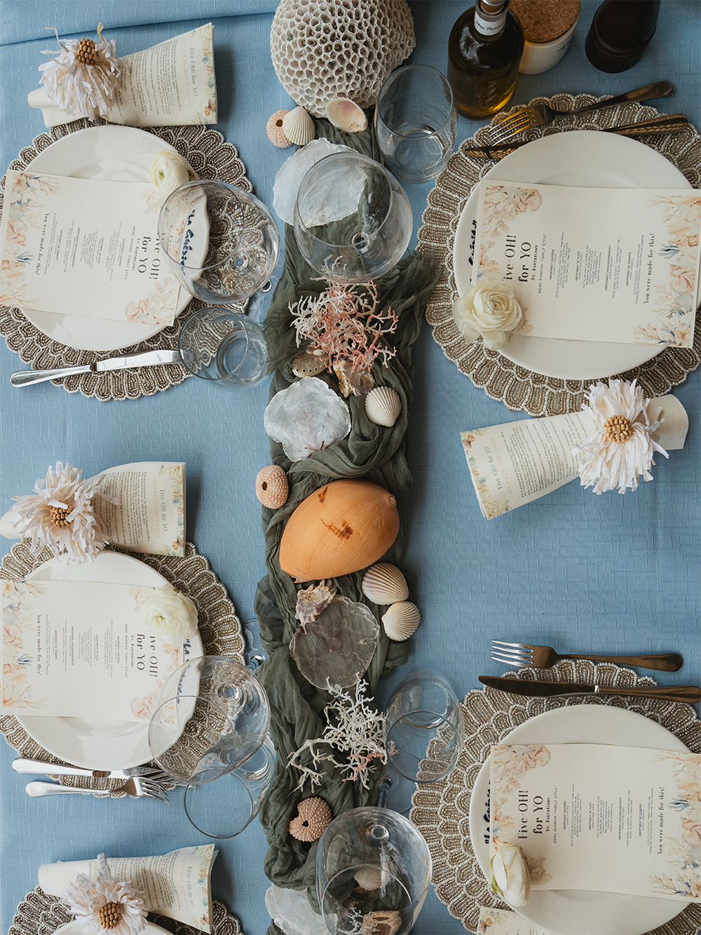 Coastal wedding table setup with blue linens, shells, and candles creating an elegant seaside atmosphere in St Barth.