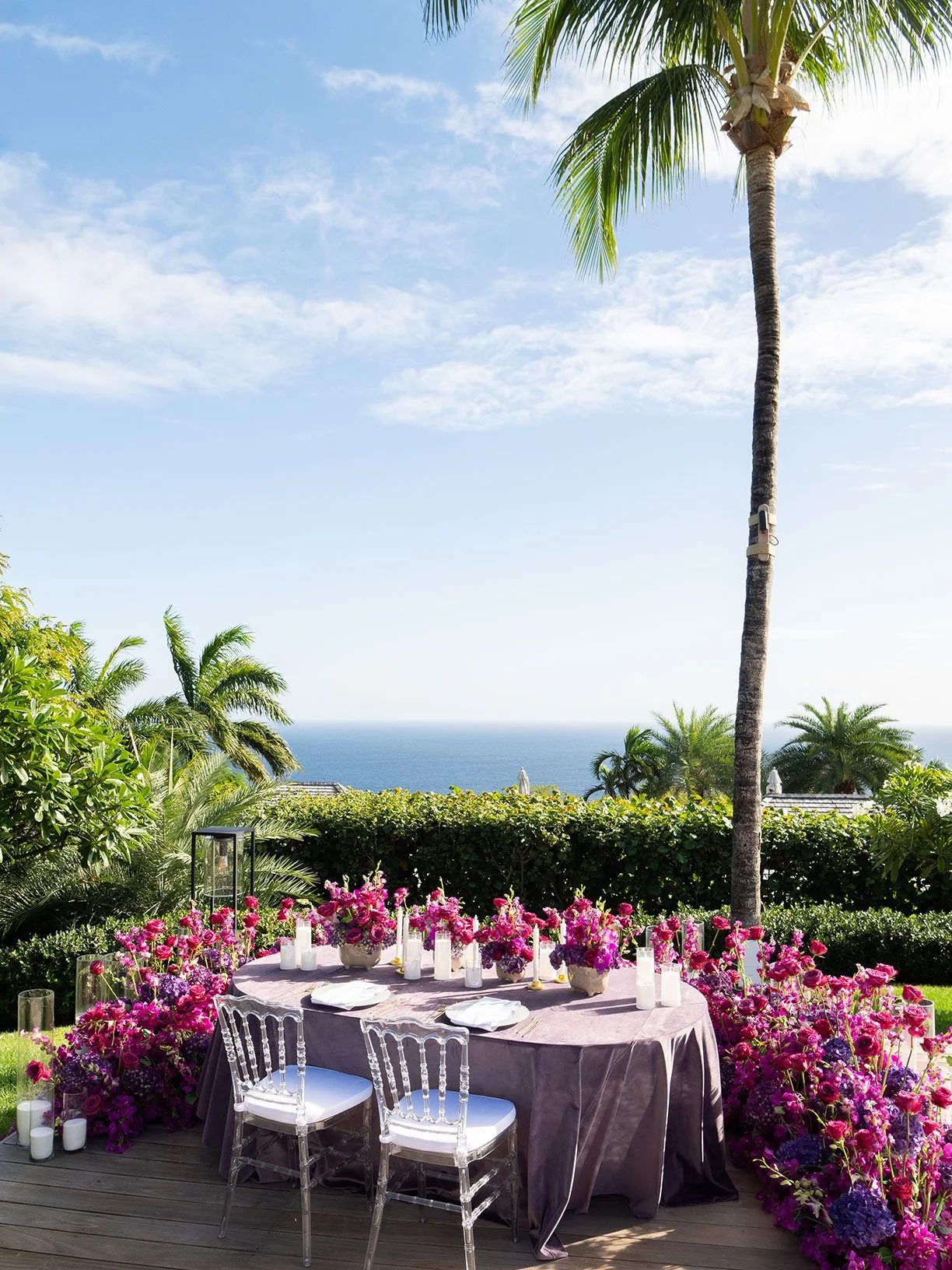 Stylish outdoor reception table decorated with violet floral centerpieces overlooking the Caribbean Sea in St Barth.