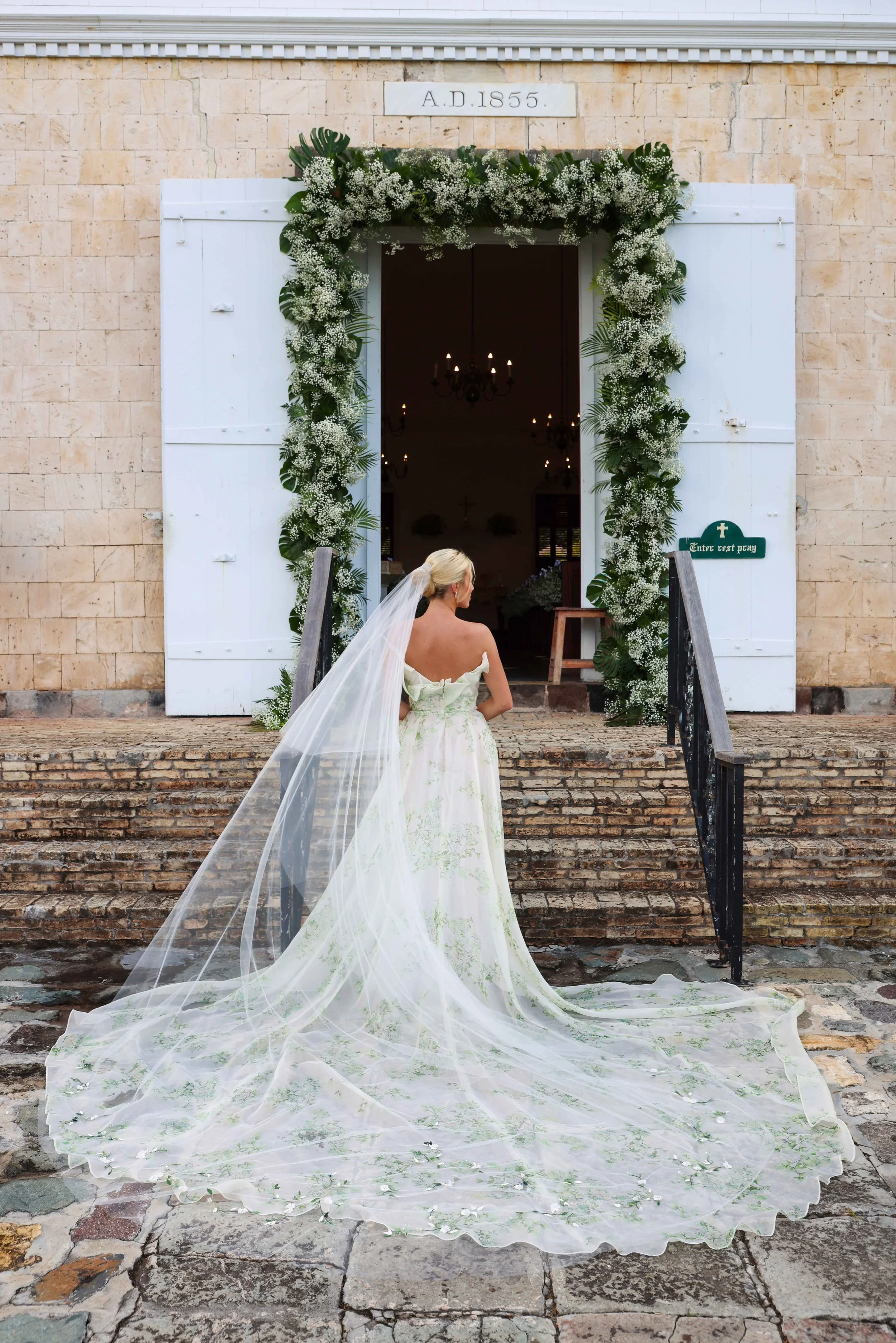 Elegant bride descending floral-decorated stone steps for a timeless wedding ceremony in St Barth.