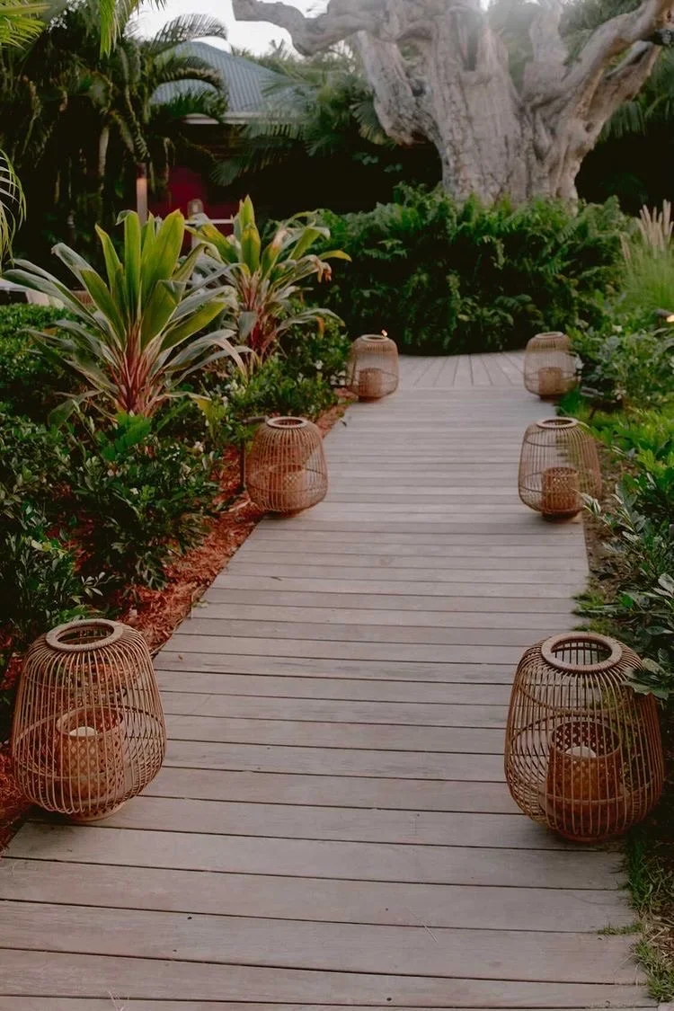 Outdoor wedding pathway lined with tropical plants and lanterns, leading to a garden ceremony setup in St Barth.