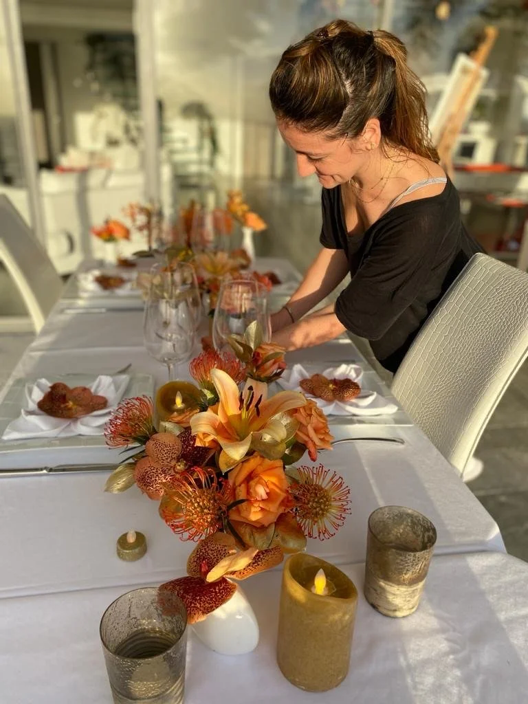 Maureen, director of the floral design team, arranging an elegant orange and gold wedding table setup in St Barth.