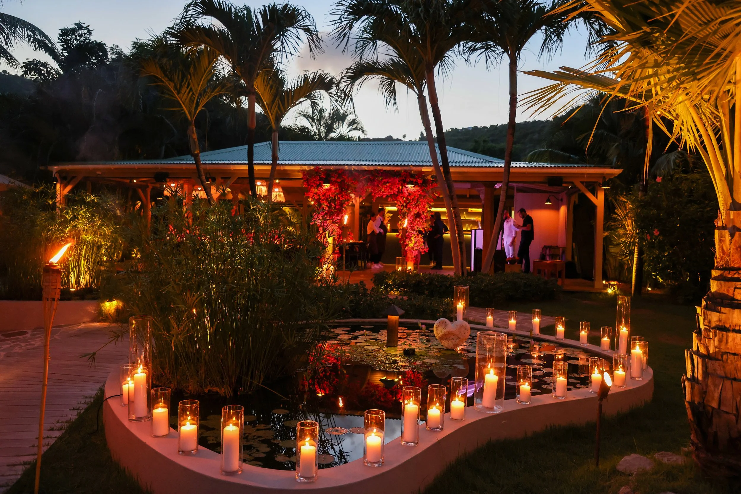 Outdoor wedding dinner illuminated by candles and string lights, surrounded by palm trees in St Barth.