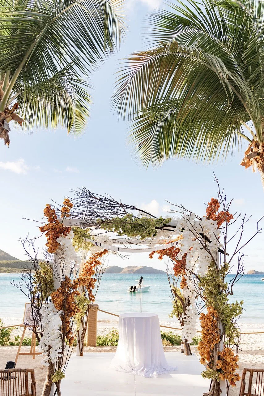 Stunning red and coral floral arch for a tropical seaside wedding ceremony in St Barth.