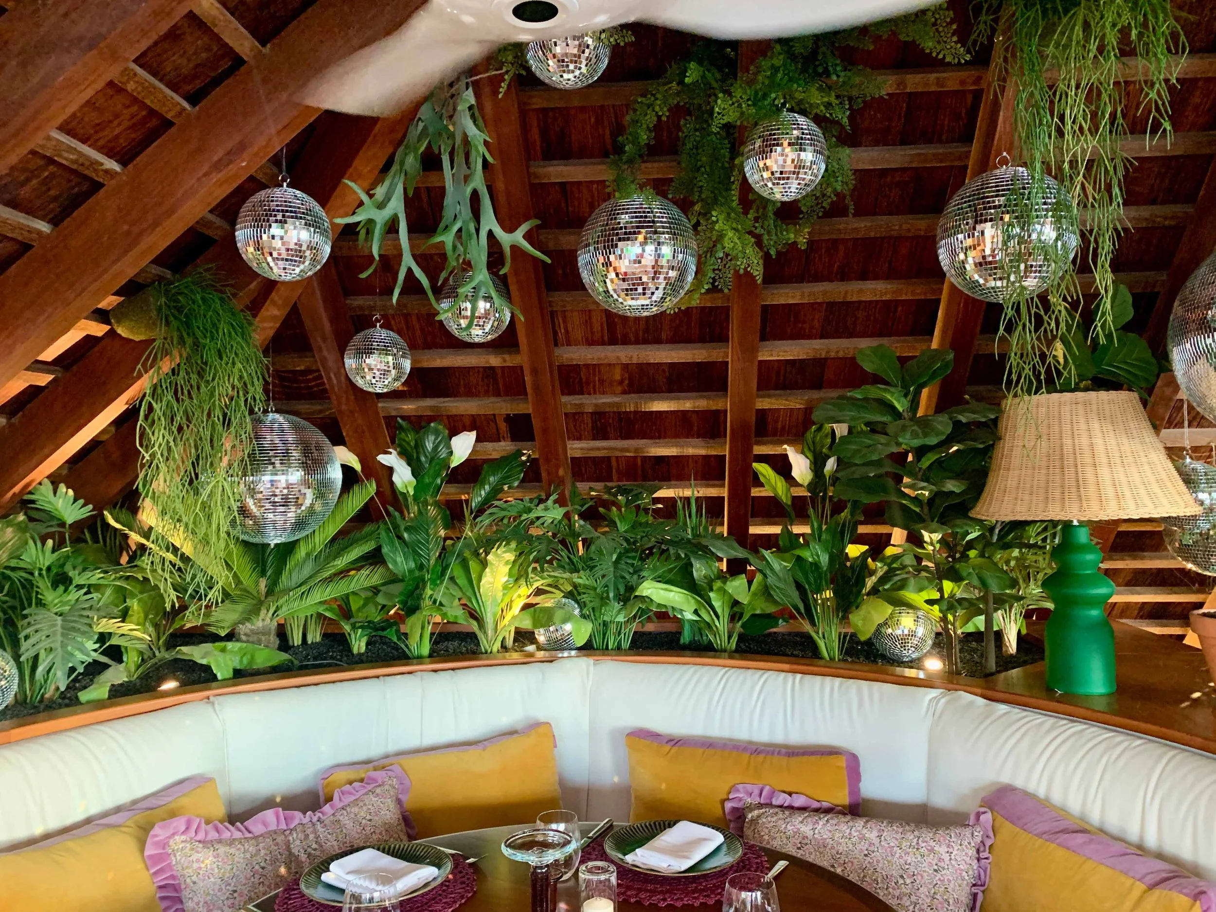 Tropical lounge area with hanging floral arrangements, mirrors, and greenery creating a warm and inviting ambiance in St Barth.