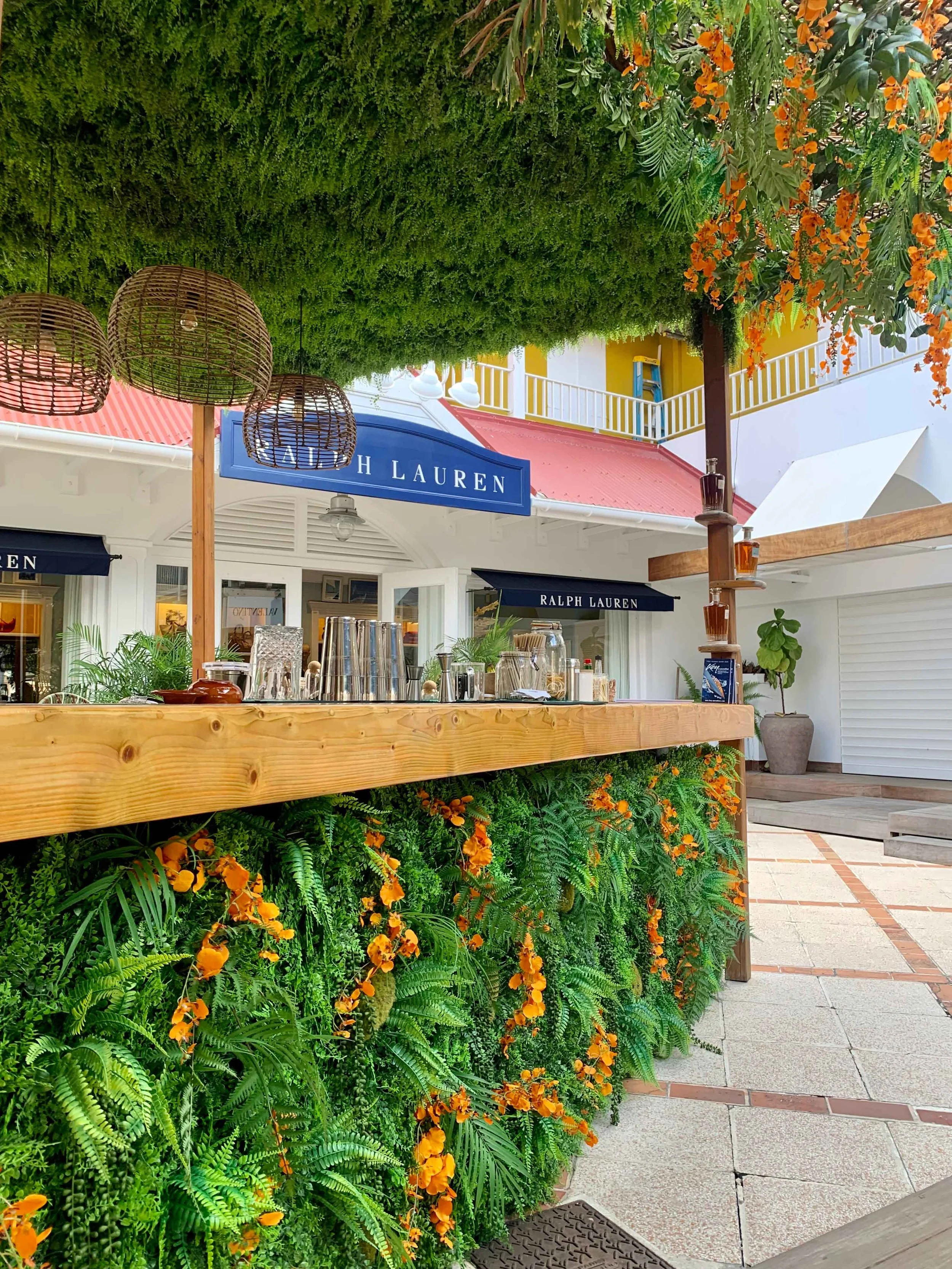 Outdoor bar shaded by a decorated tree with yellow lemons and greenery, offering a relaxed tropical ambiance in St Barth.
