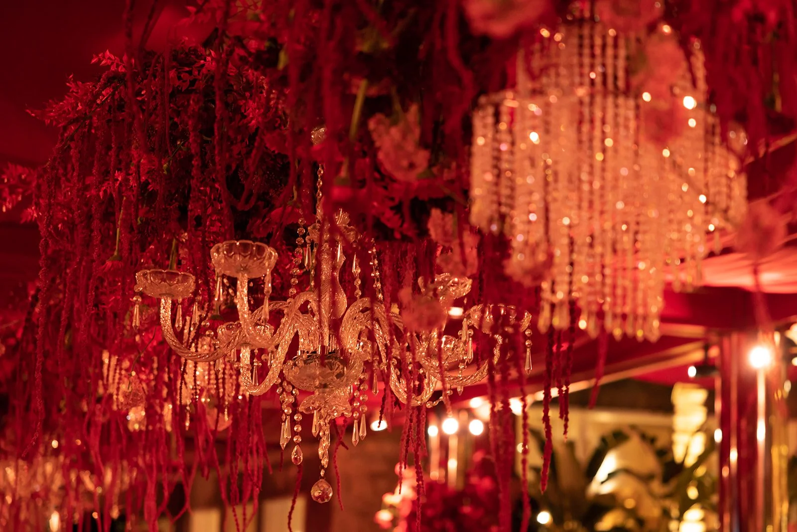 Un lustre en cristal suspendu, entouré de décorations rouges, dans une ambiance chaleureuse et élégante.
