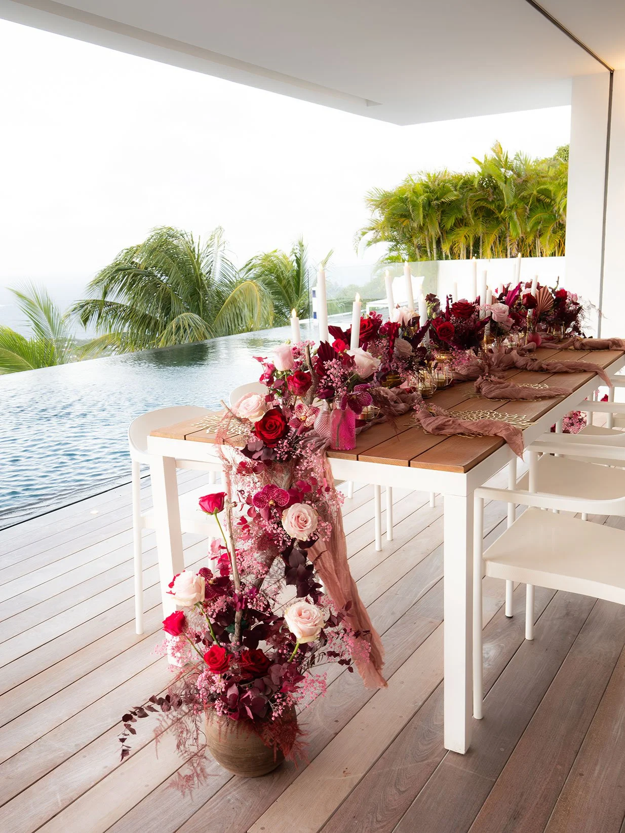 Romantic beachside table decorated with a red and pink floral arch and ocean view in St Barth.
