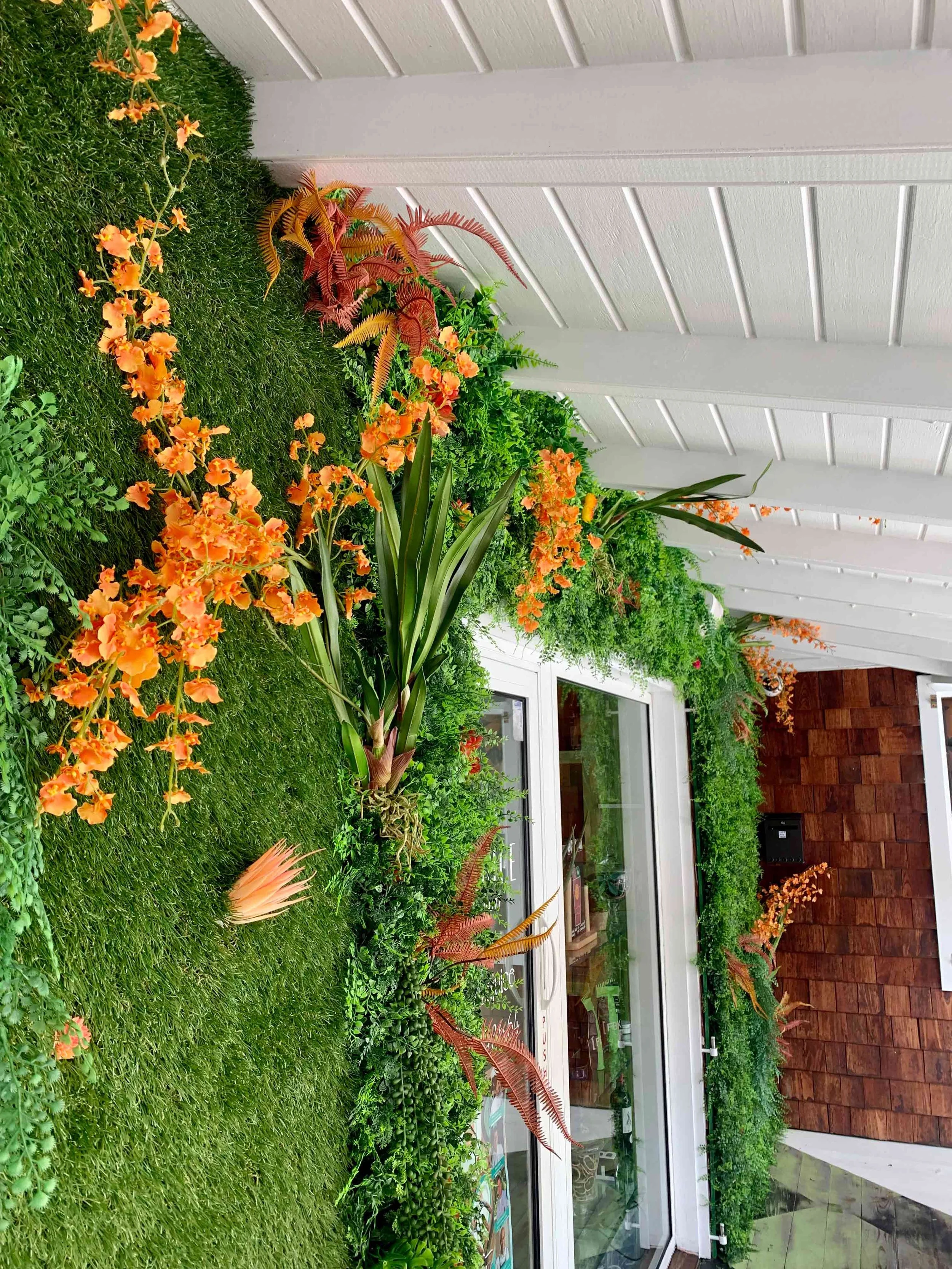 Green wall decorated with cascading orange flowers for a bright and tropical interior design in St Barth.