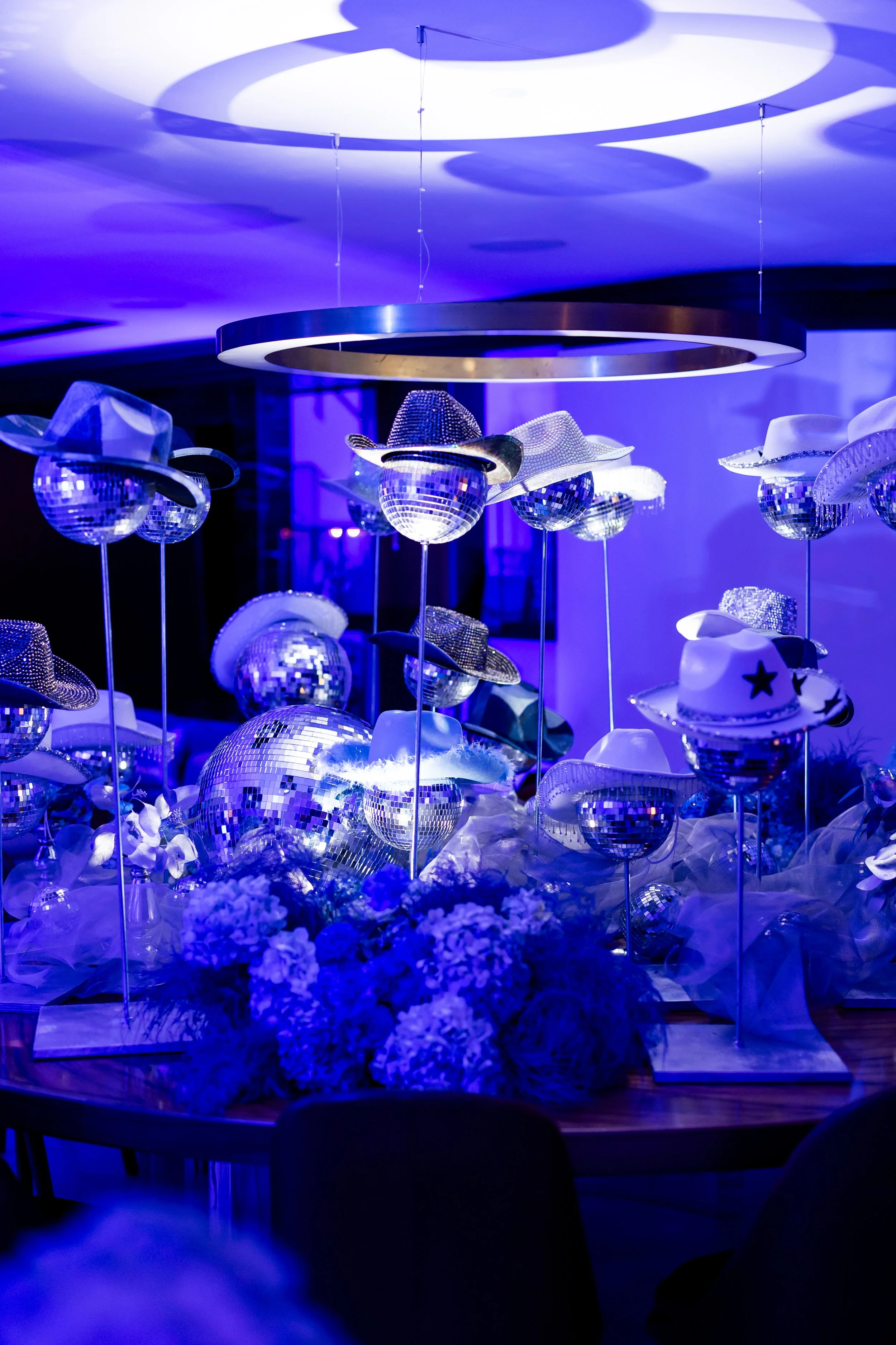 Décor féerique avec des balles en miroir et des chapeaux de cowboy, illuminés en lumière bleue, ambiance festive