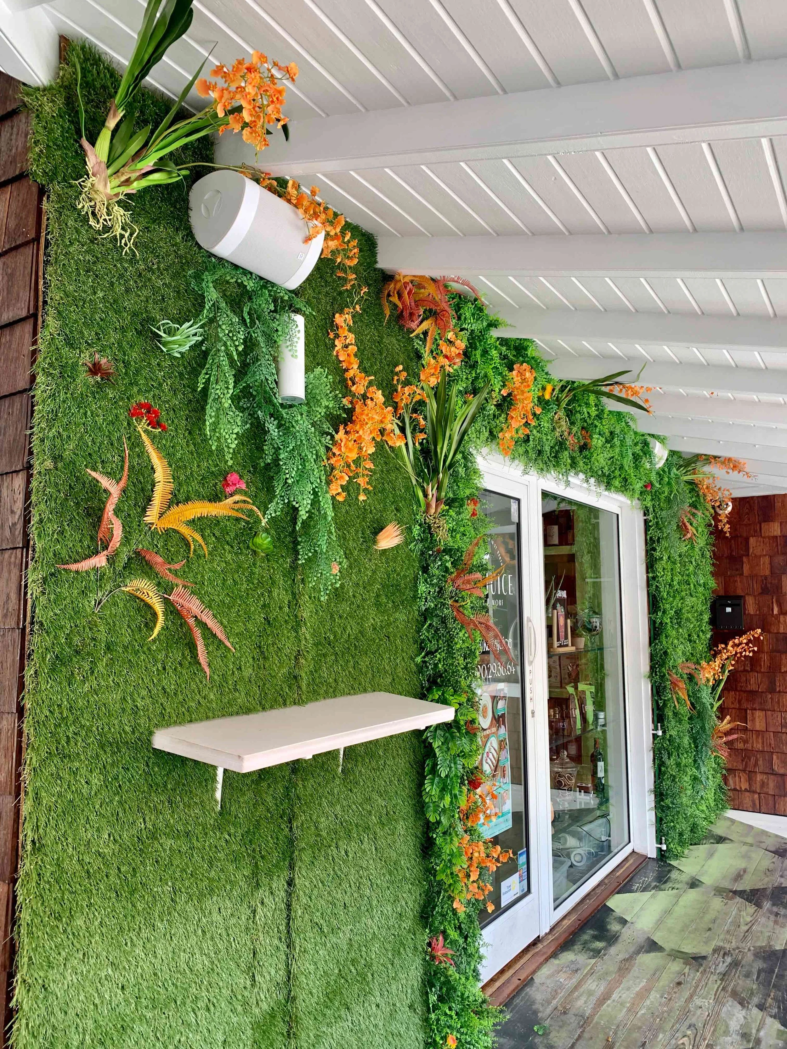 Vertical garden wall decorated with orange flowers and white entryway for a modern tropical style in St Barth.