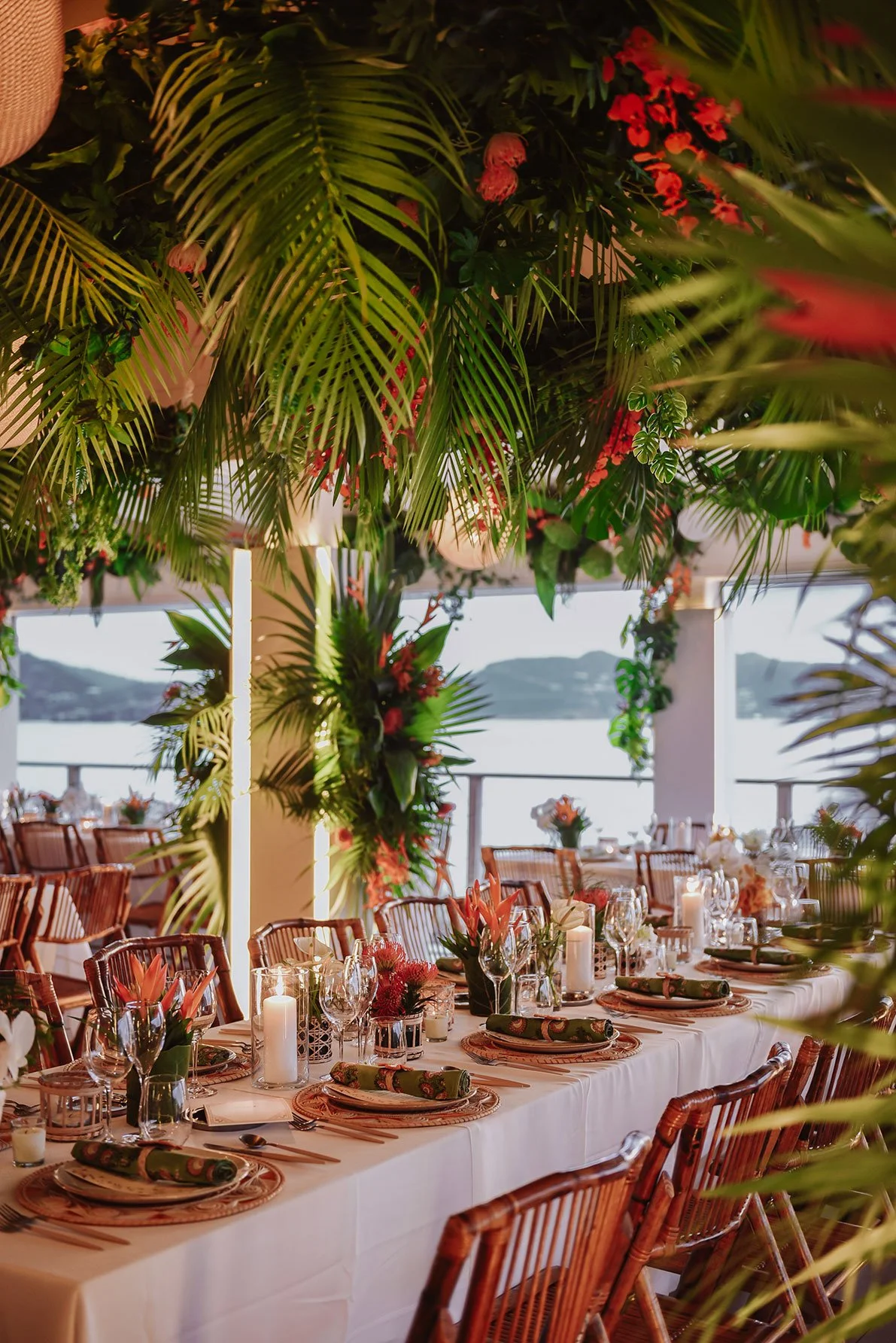 Tropical-inspired wedding reception table with gold accents, greenery, and warm candlelight in St Barth.
